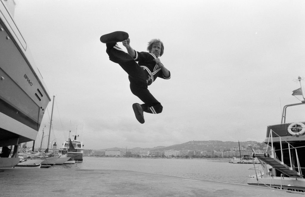 Chuck Norris doing a karate kick at a port in Cannes, France | Photo: DEUTSCH Jean-Claude/GYSEMBERGH Benoit/Paris Match via Getty Images