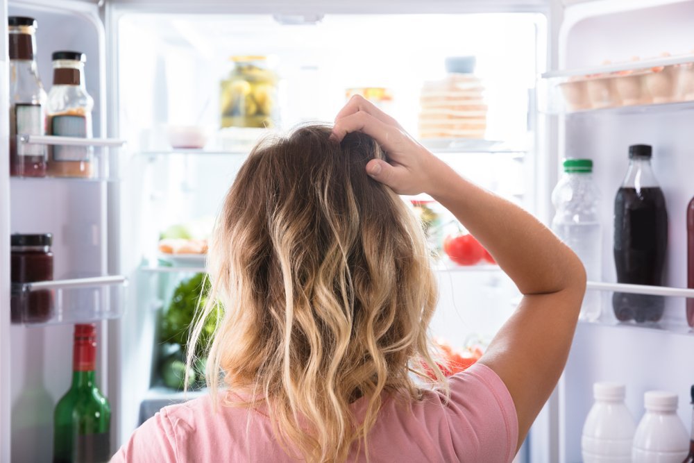 Confused Woman Looking In Open Refrigerator. | Source: Shutterstock