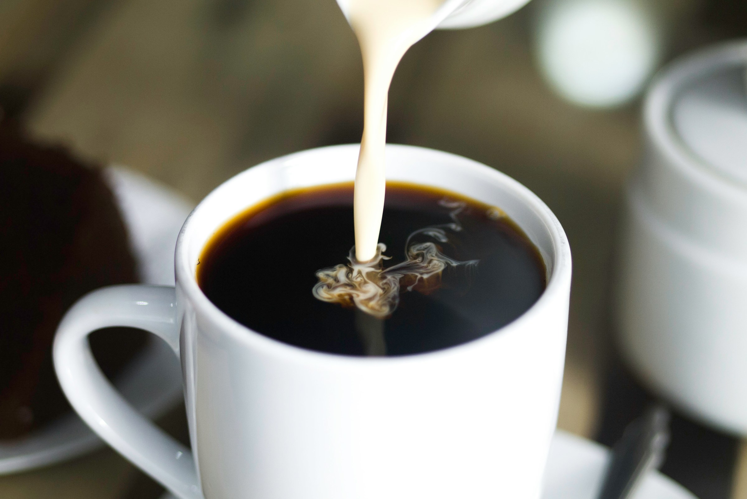 A person pouring milk into coffee | Source: Unsplash