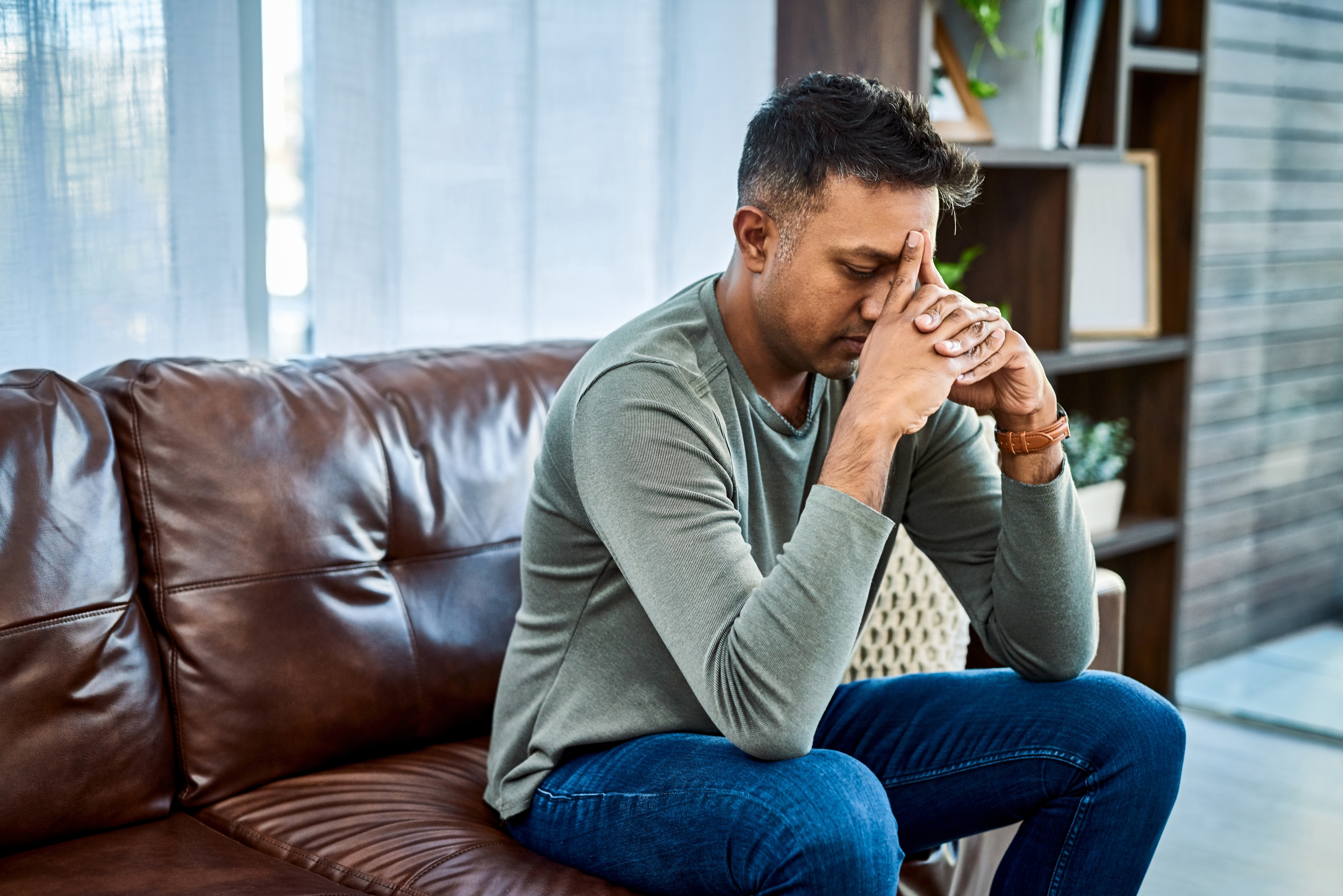 An upset man sitting on a couch | Source: Getty Images