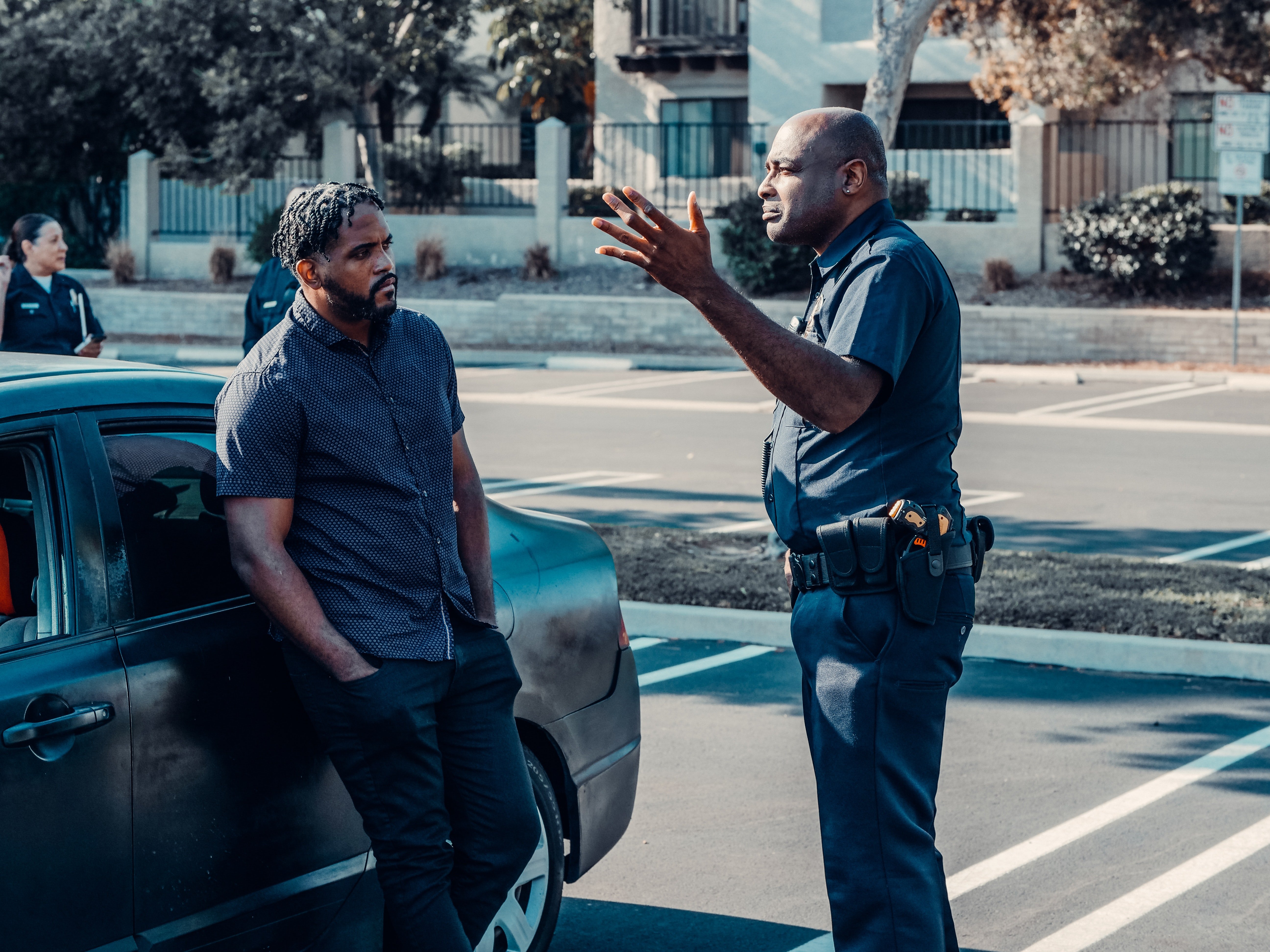 An officer talking to a man leaning against a car. | Pexels/ Kindel Media