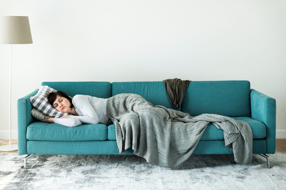 A woman sleeping comfortably on a couch | Photo: Shutterstock/Rawpixel.com