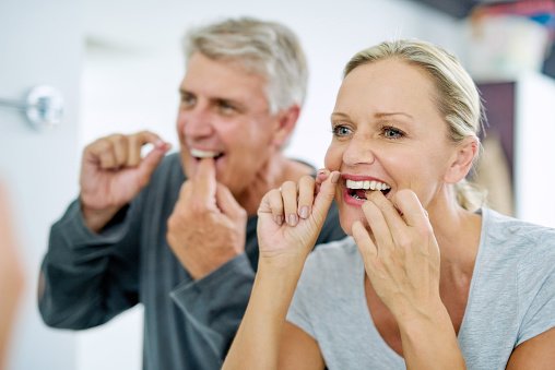 Photo d'un couple mature utilisant le fil dentaire dans la salle de bain. | Photo : Getty Images Photo d'un couple mature utilisant le fil dentaire dans la salle de bain. | Photo : Getty Images