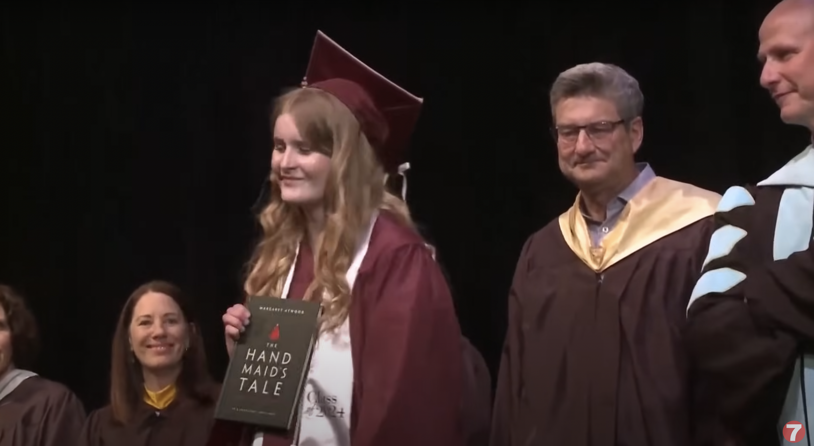 Annabelle Jenkins holding the graphic novel adaptation of Margaret Atwood's "The Handmaid's Tale" on her graduation ceremony, as seen in a video dated May 29, 2024 | Source: YouTube/ktvb7