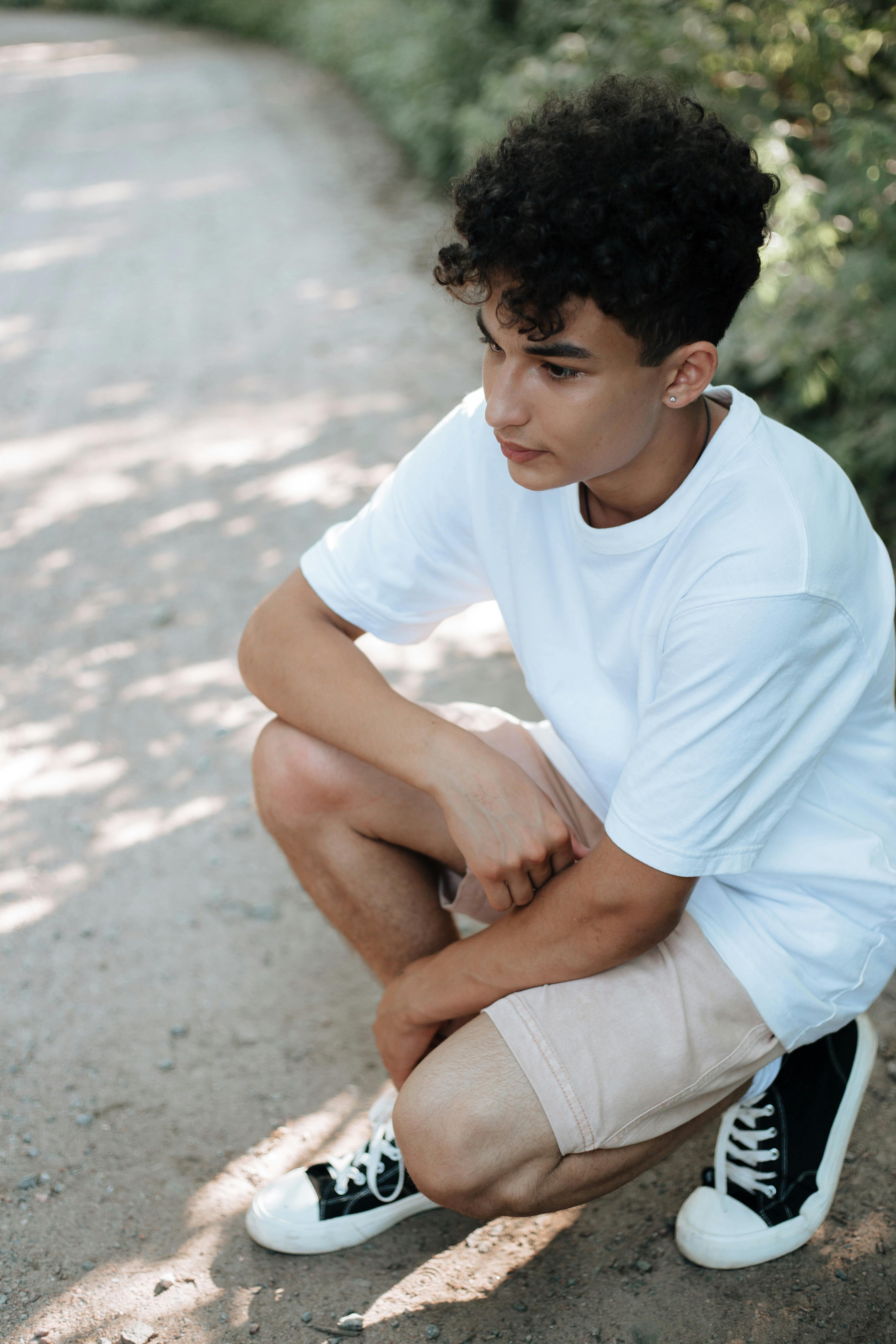 A teenage boy crouching on footpath | Source: Pexels