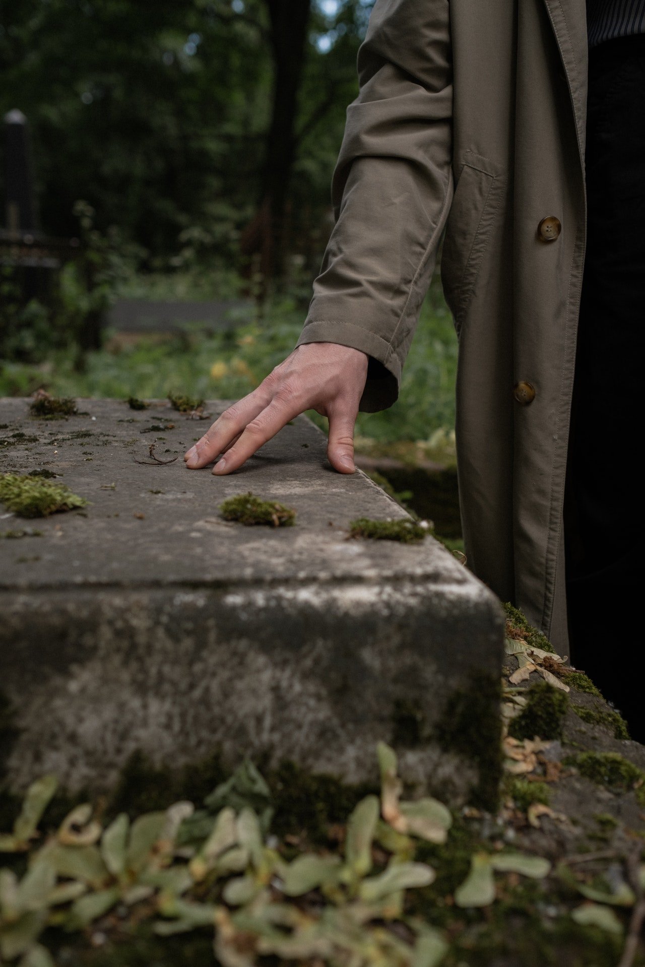 Un hombre visitando una tumba en un cementerio. | Foto: Pexels
