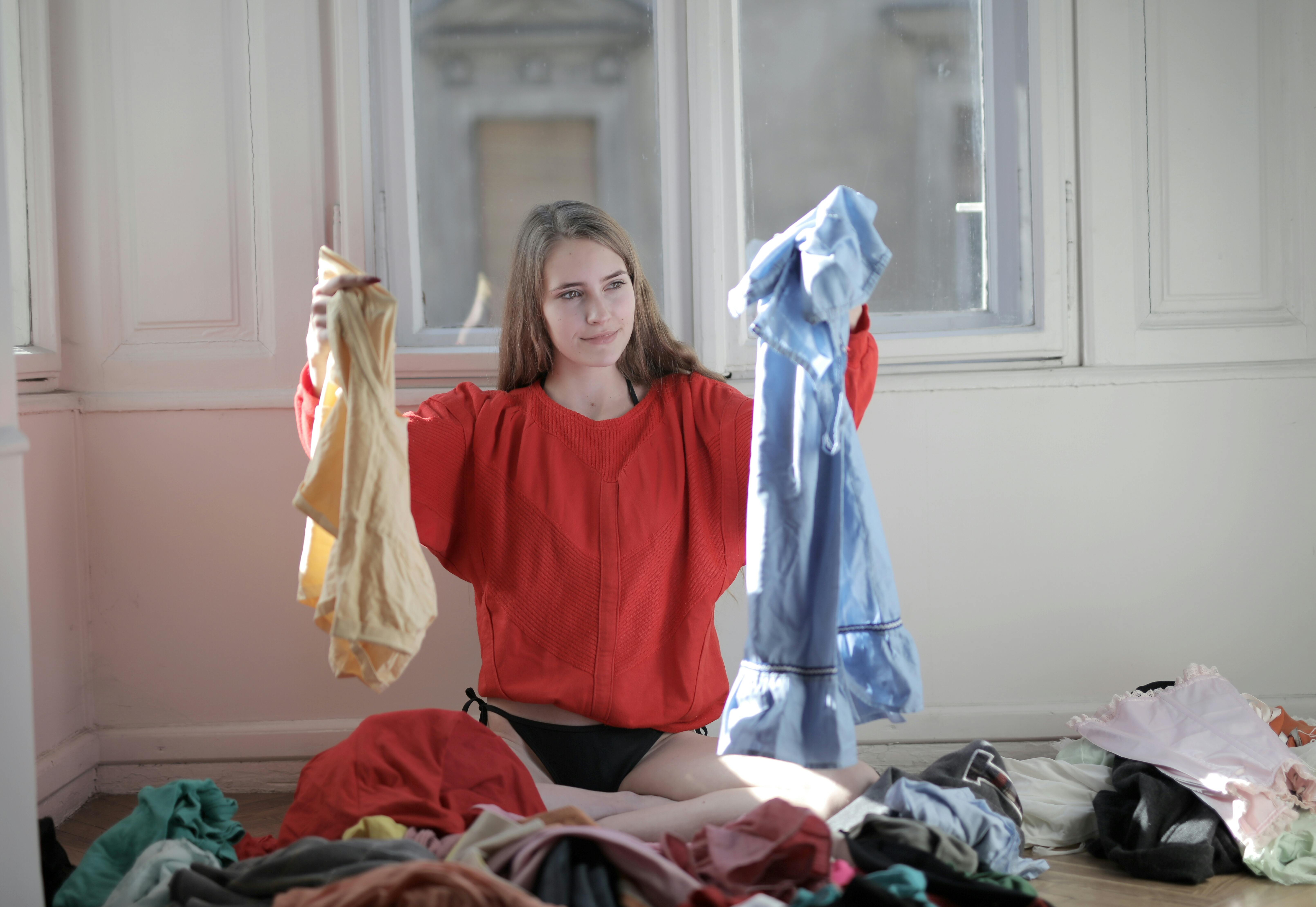 Woman holding up pieces of clothing from the laundry | Source: Pexels