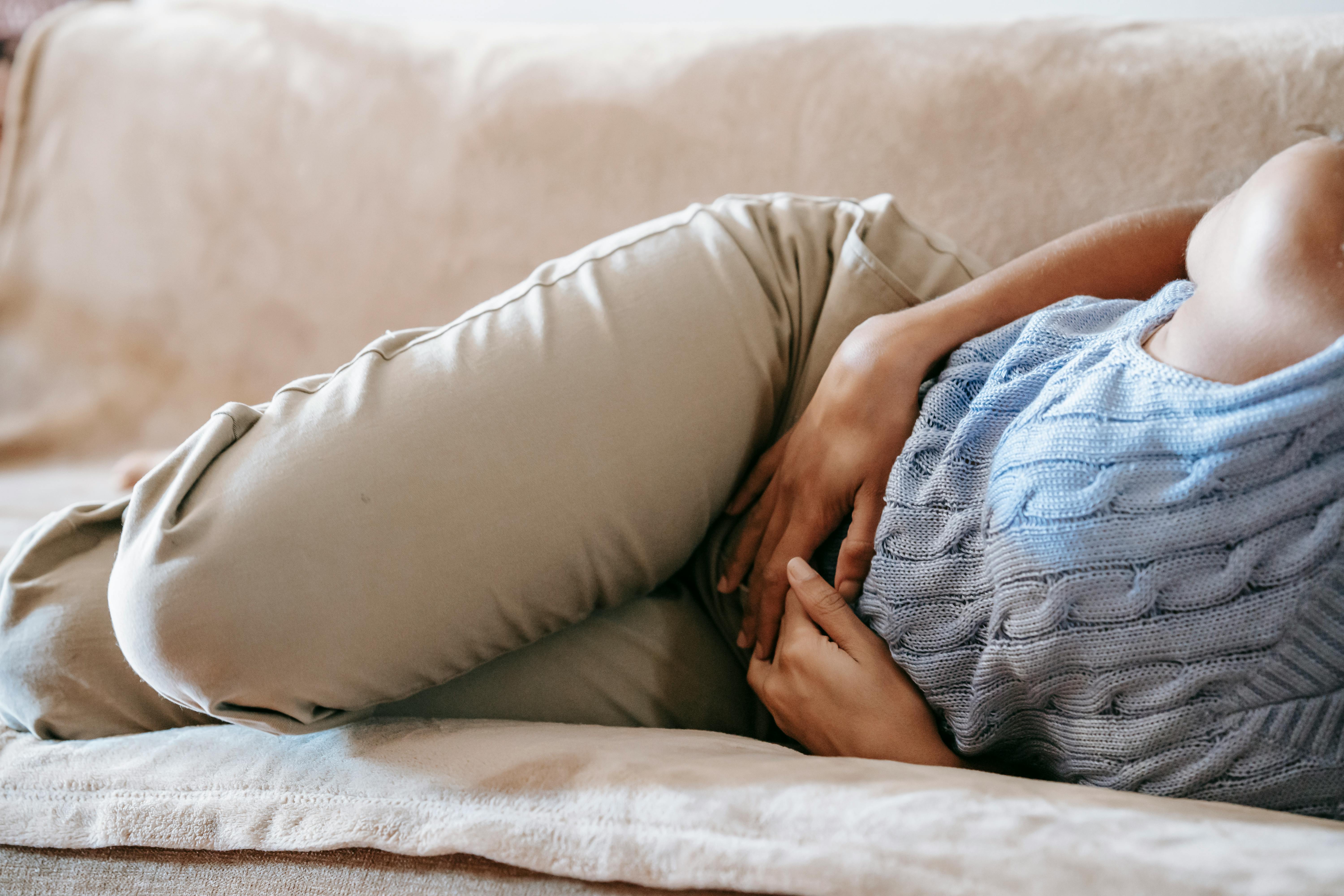 A woman clutching their stomach | Source: Pexels
