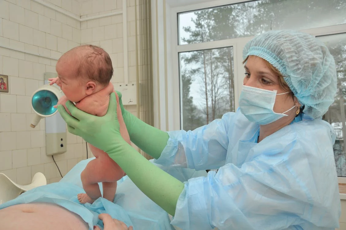 Enfermera mostrando recién nacido a su madre. | Foto: Pexels