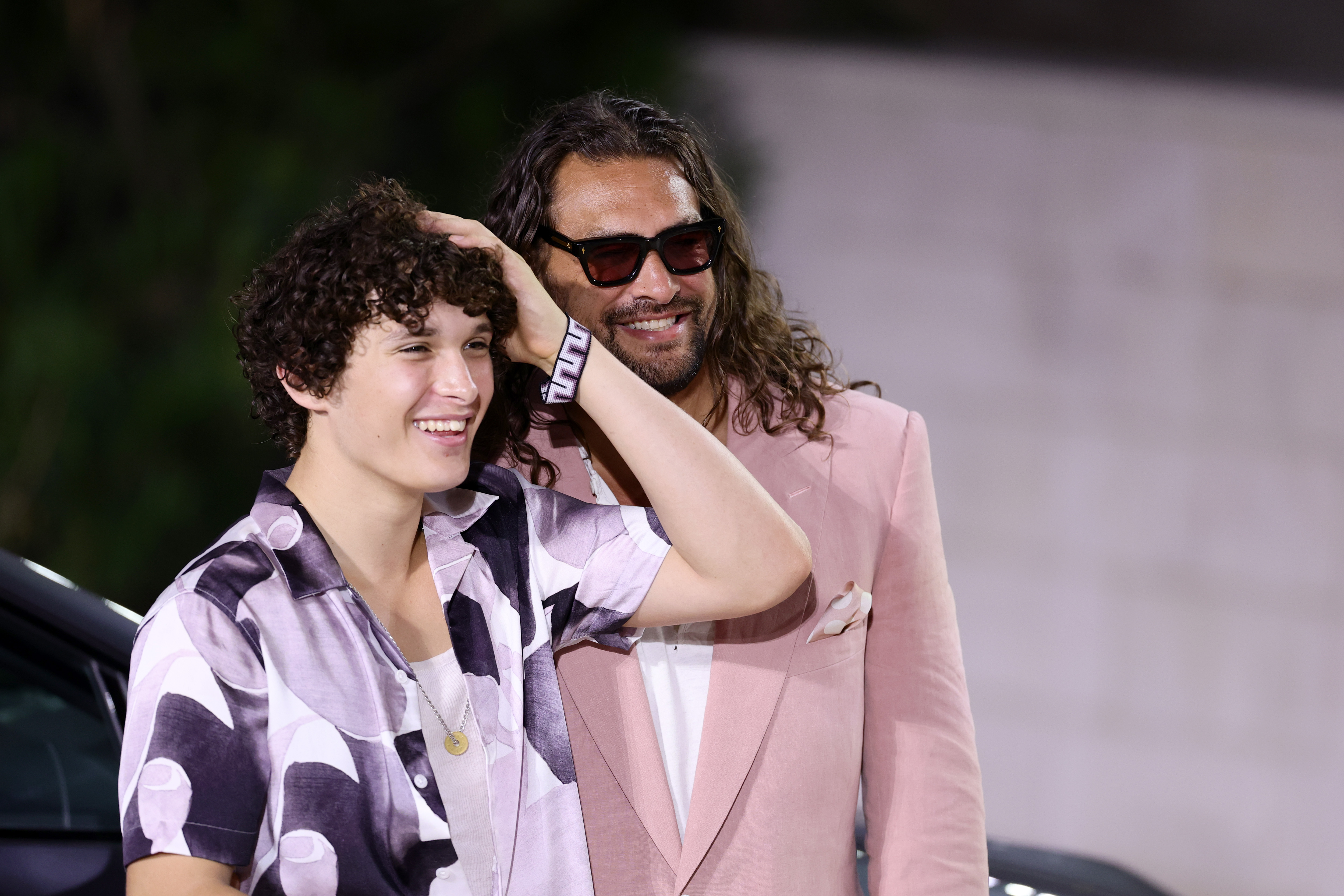 Nakoa-Wolf Momoa flashed a wide smile as he stood confidently next to Jason Momoa during the "In the Hand of Dante" premiere at the Venice Film Festival, both soaking up the spotlight in relaxed style.