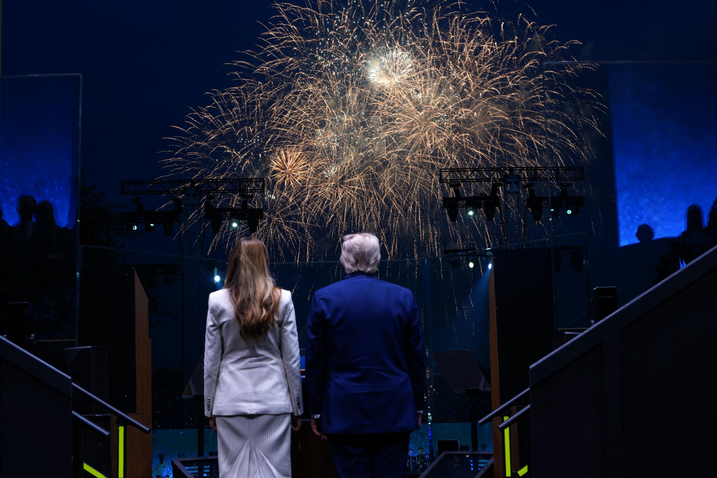 President Donald Trump and First Lady Melania Trump watch a fireworks display celebrating the Army’s 250th anniversary, lighting up the National Mall at night.
