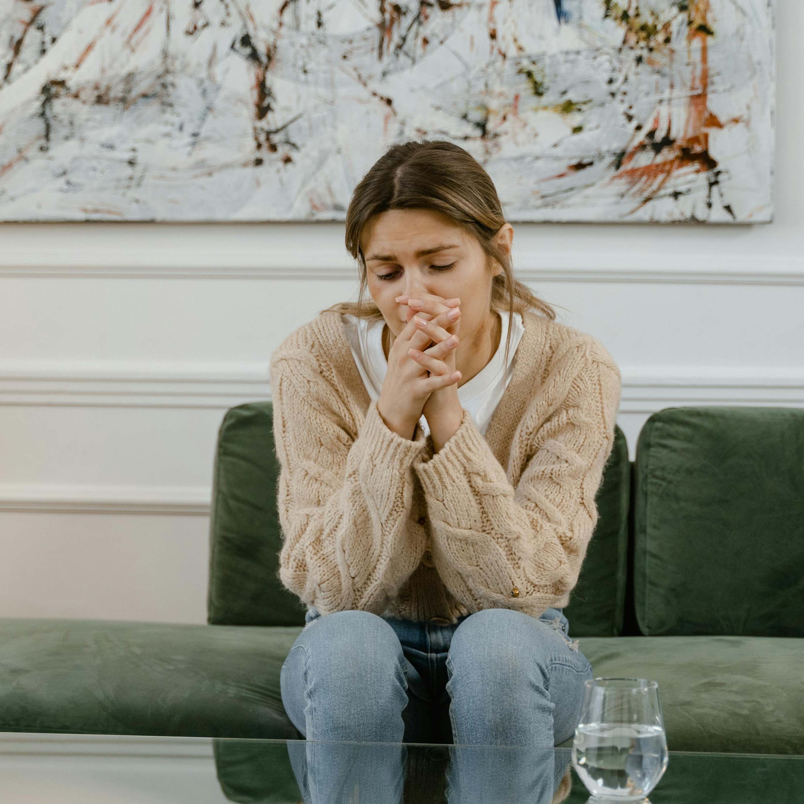 An upset-looking woman sitting on a sofa | Source: Pexels