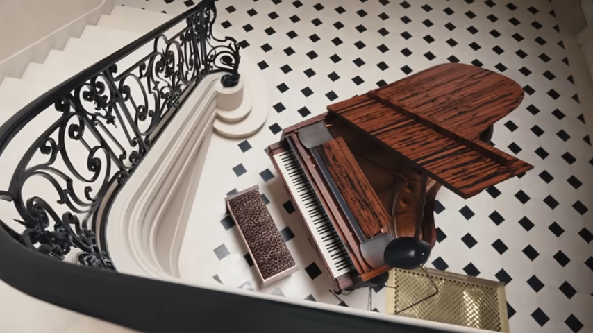 A top-down look at the custom Steinway grand piano, showing off its rich Macassar ebony wood and a leopard-print bench. | Source: YouTube/@Archdigest