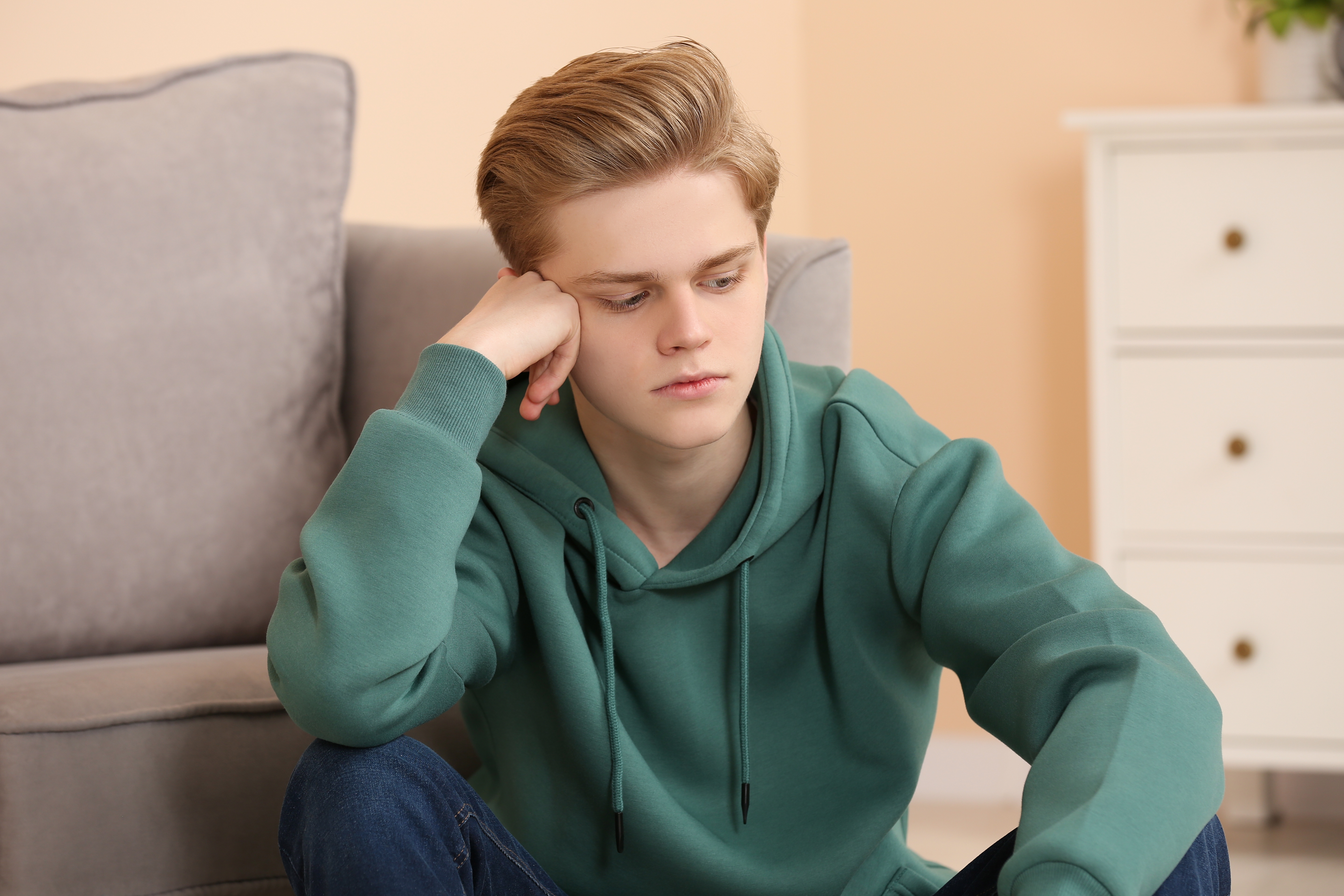 A distressed teenage boy sitting on the floor | Source: Shutterstock