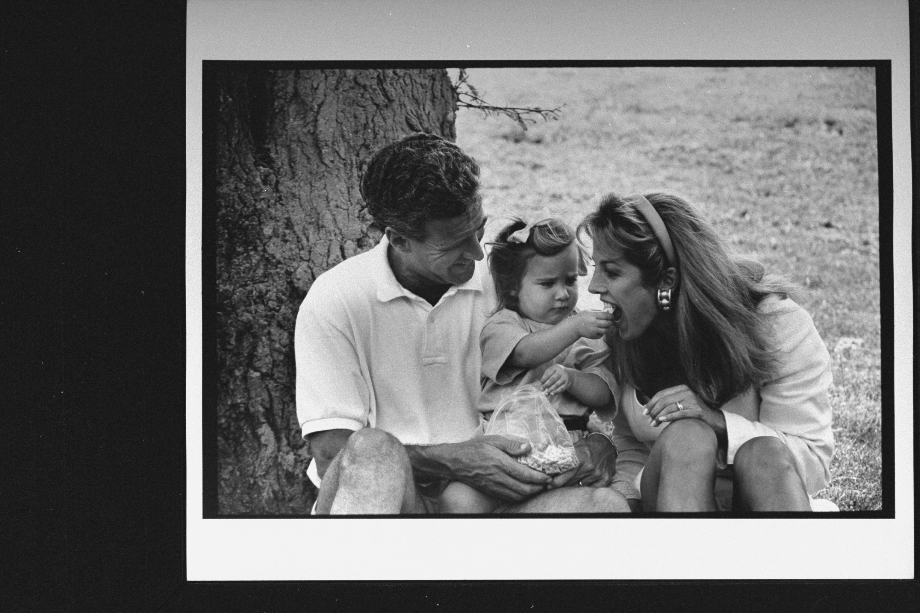 Denise Austin and Jeff Austin are pictured with their 21-month-old daughter, Kelly, who is feeding her mother a cracker while sitting under a tree in a park near their home, on June 3, 1992 | Source: Getty Images