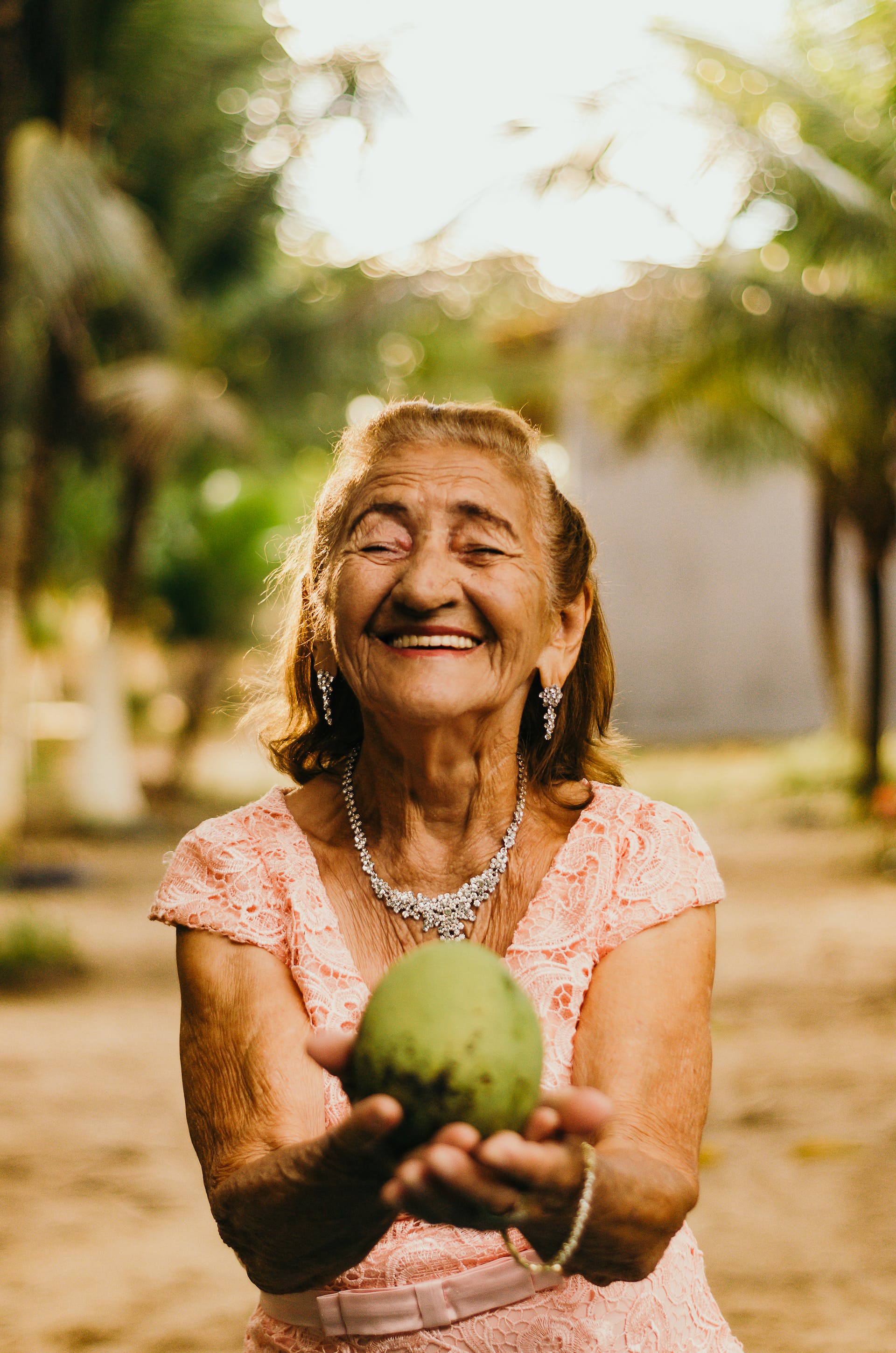 Old woman smiling and holding a coconut | Source: Pexels