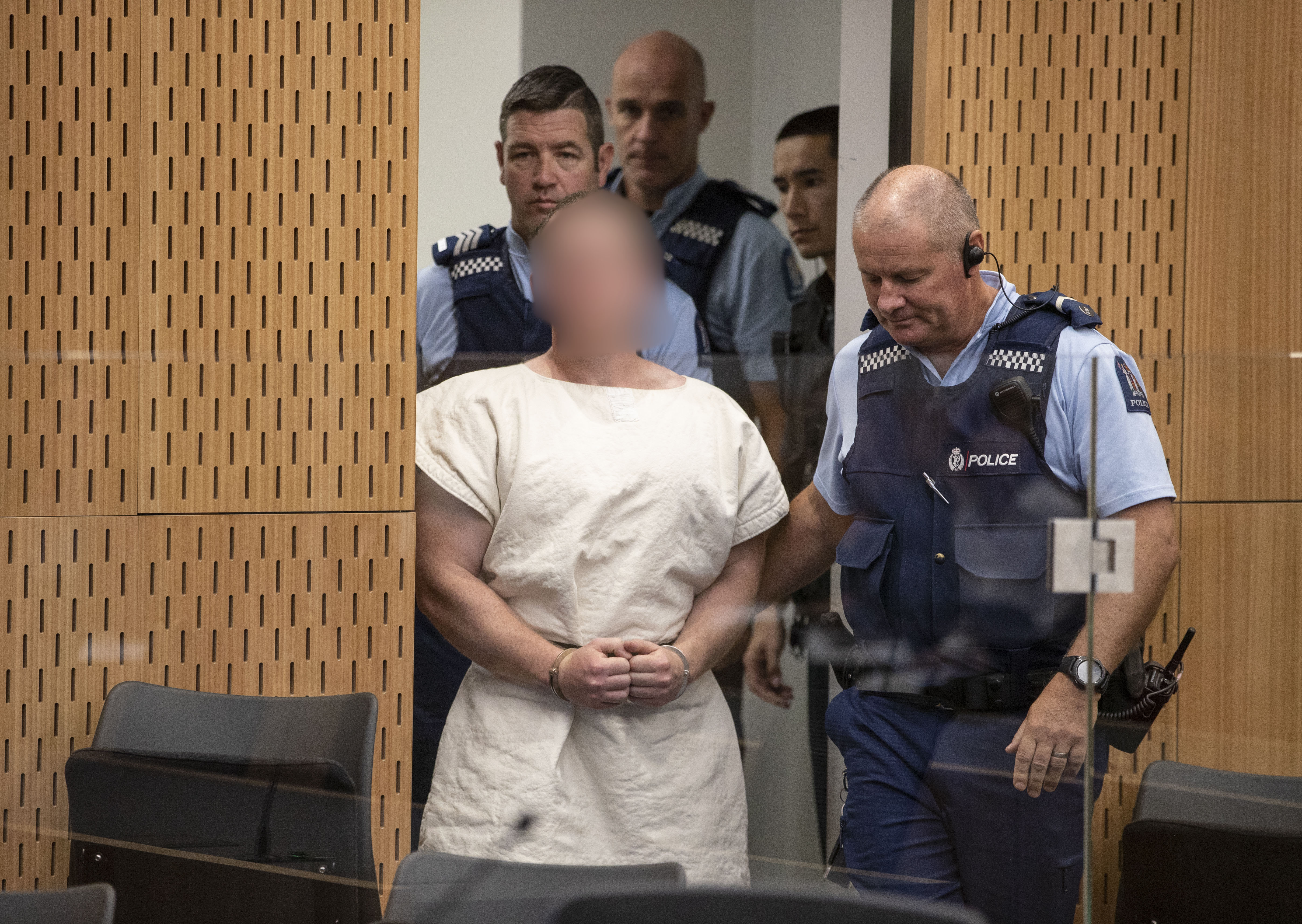 Brenton Tarrant being led into the courtroom by several police officers at the Christchurch District Court | Photo: Getty Images