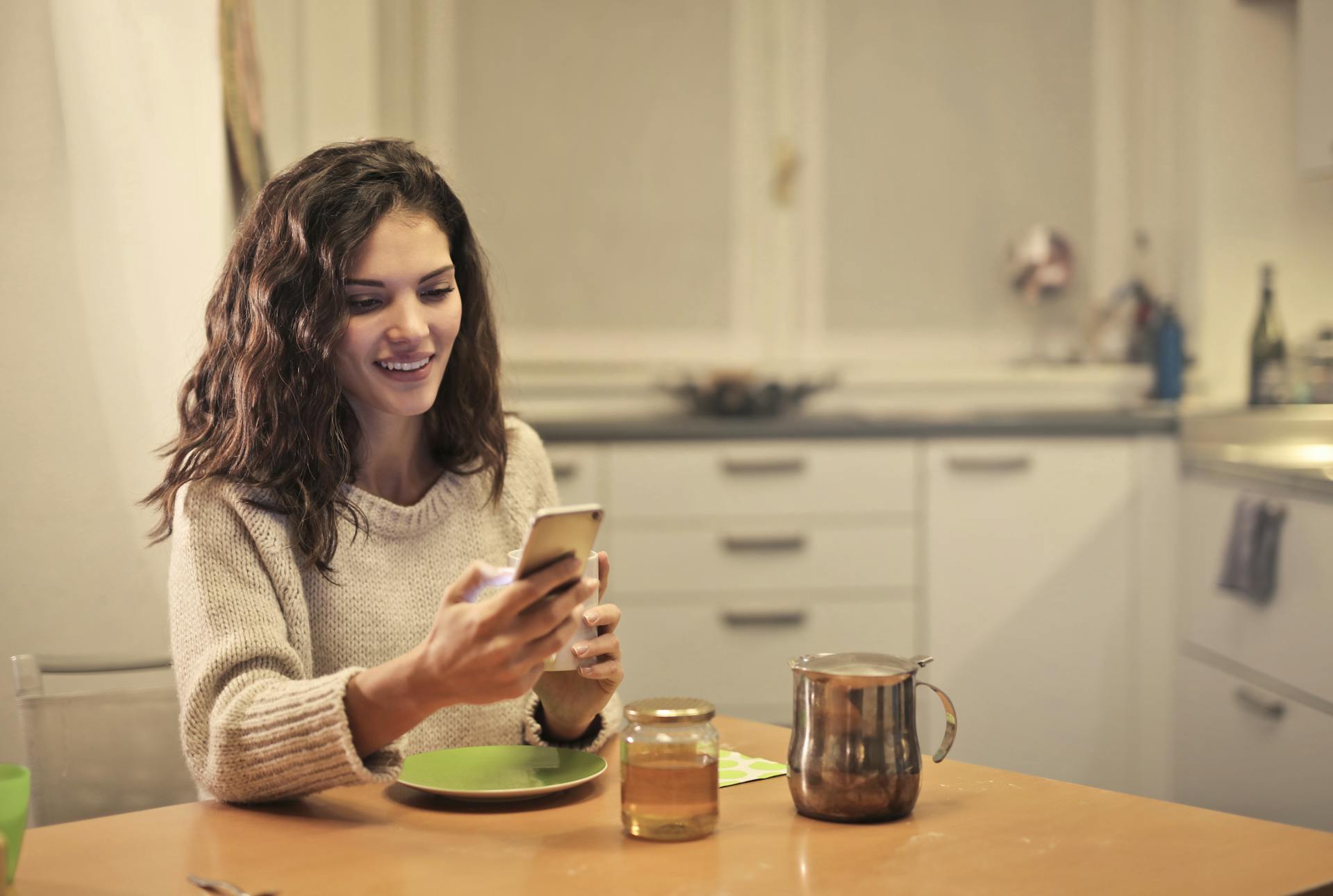 A young woman drinking tea and using her phone | Source: Pexels