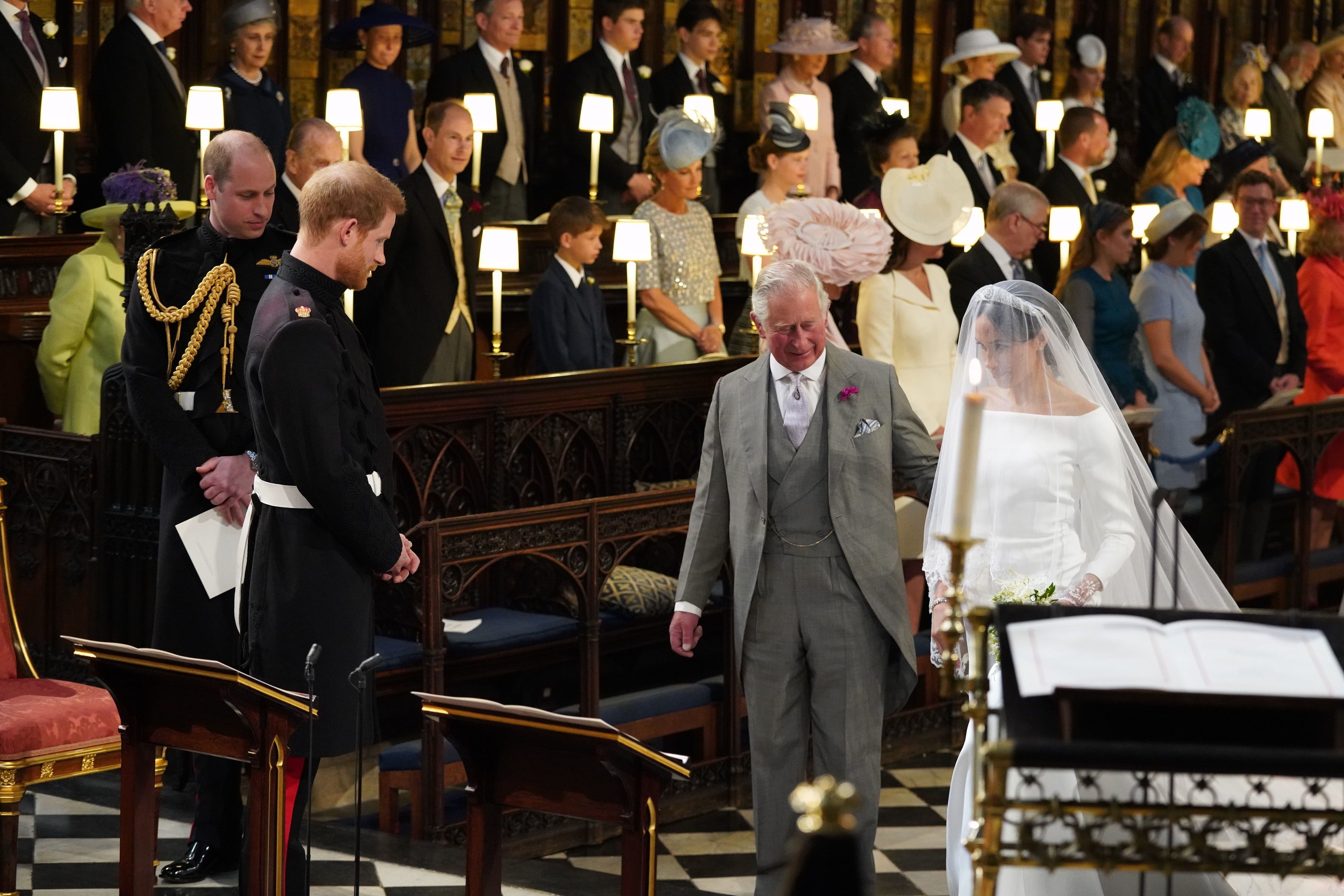 Prince Harry looks at his bride, Meghan Markle, as she arrives at the altar accompanied by Prince Charles, Prince of Wales | Source: Getty Images 