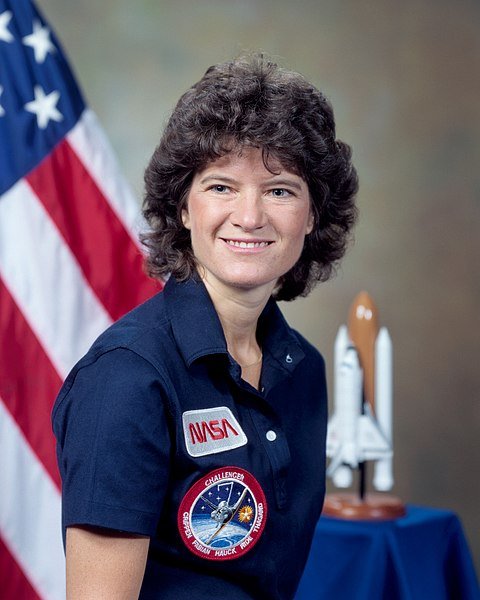 Portrait of Sally Ride in NASA uniform with U.S. flag in the background | Source: Wikimedia Commons