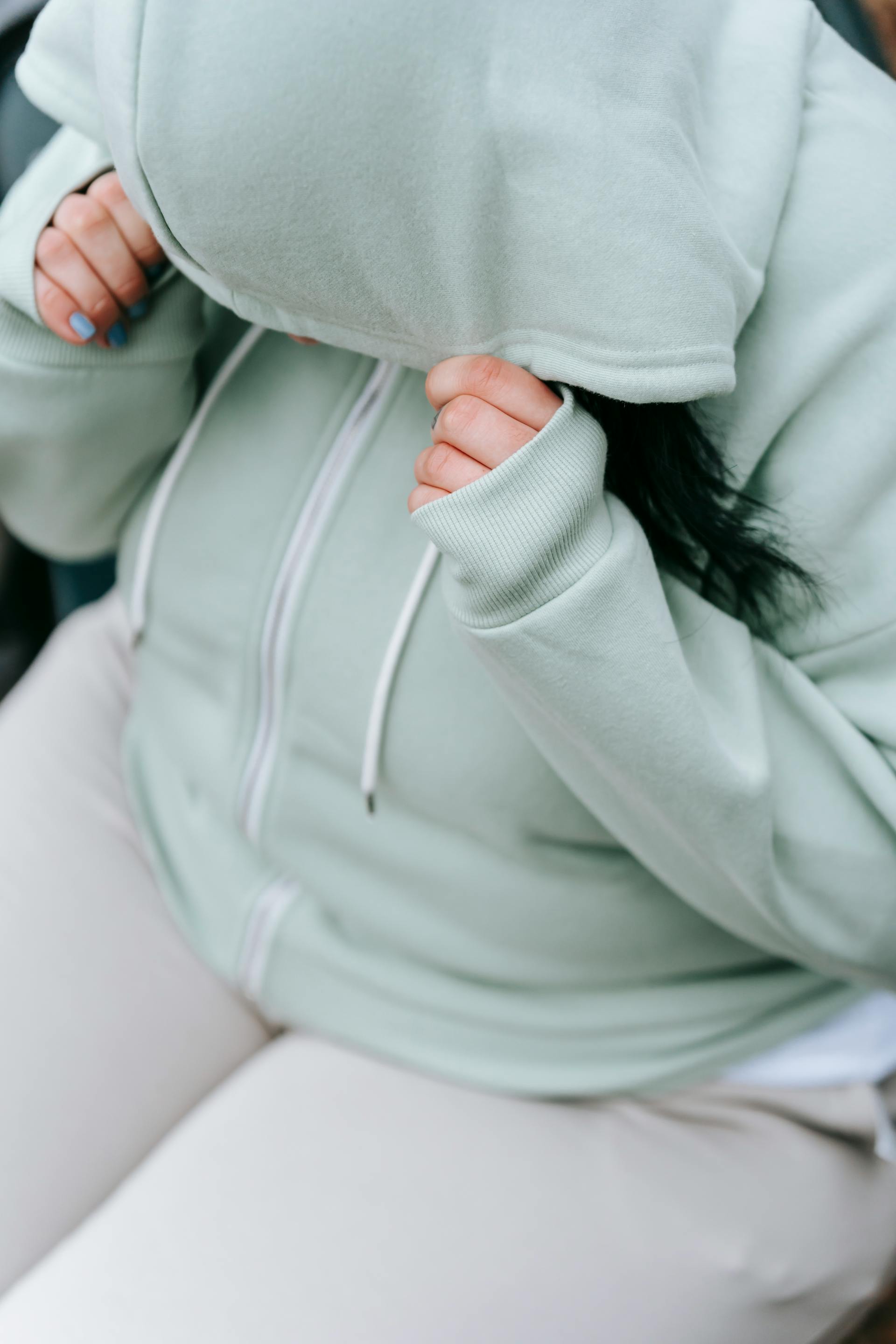 A woman in sportswear hiding her face with her hoodie's cap | Source: Pexels
