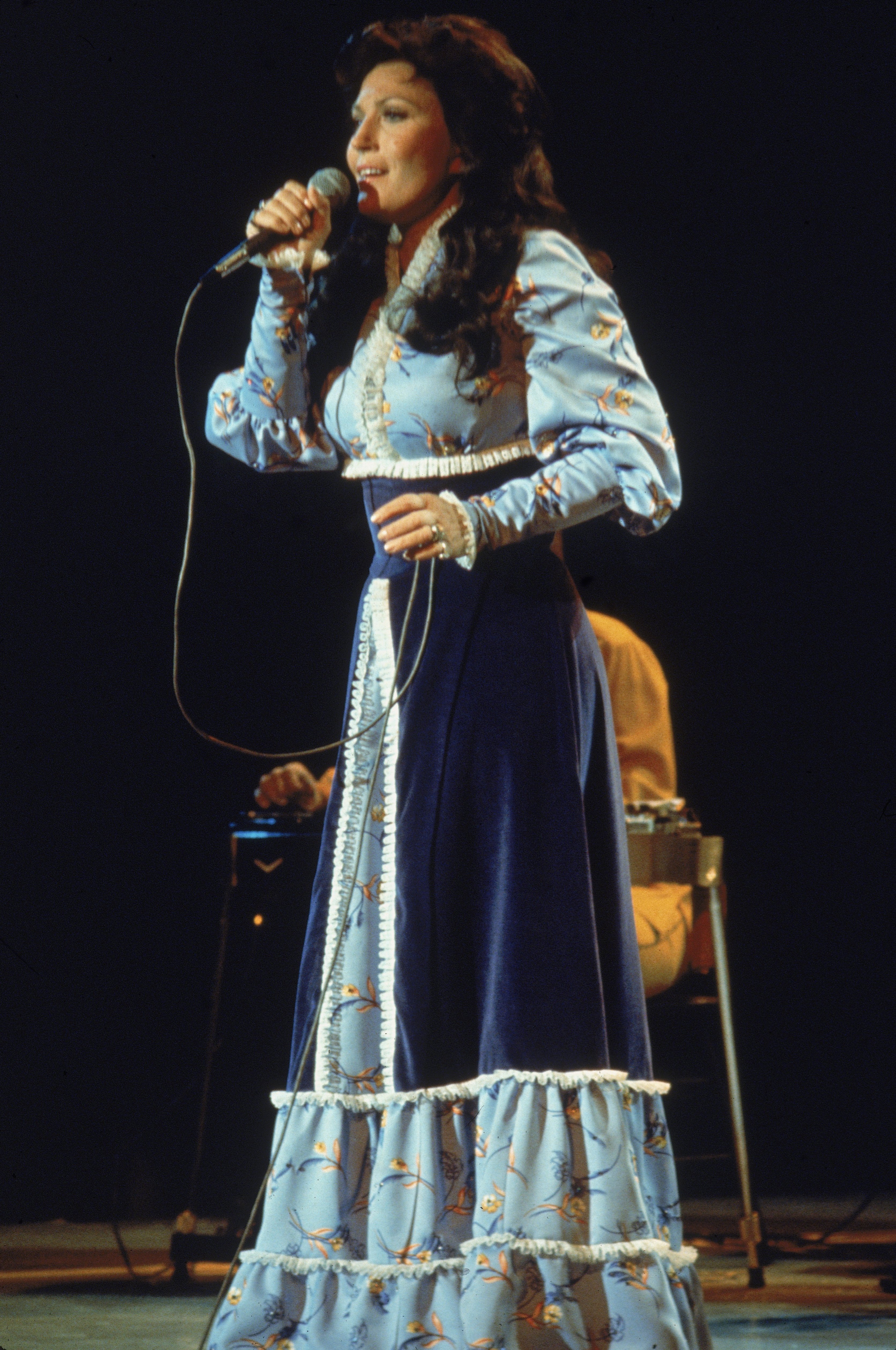 Loretta Lynn performs on stage, wearing a long dress, circa 1980. | Source: Getty Images.