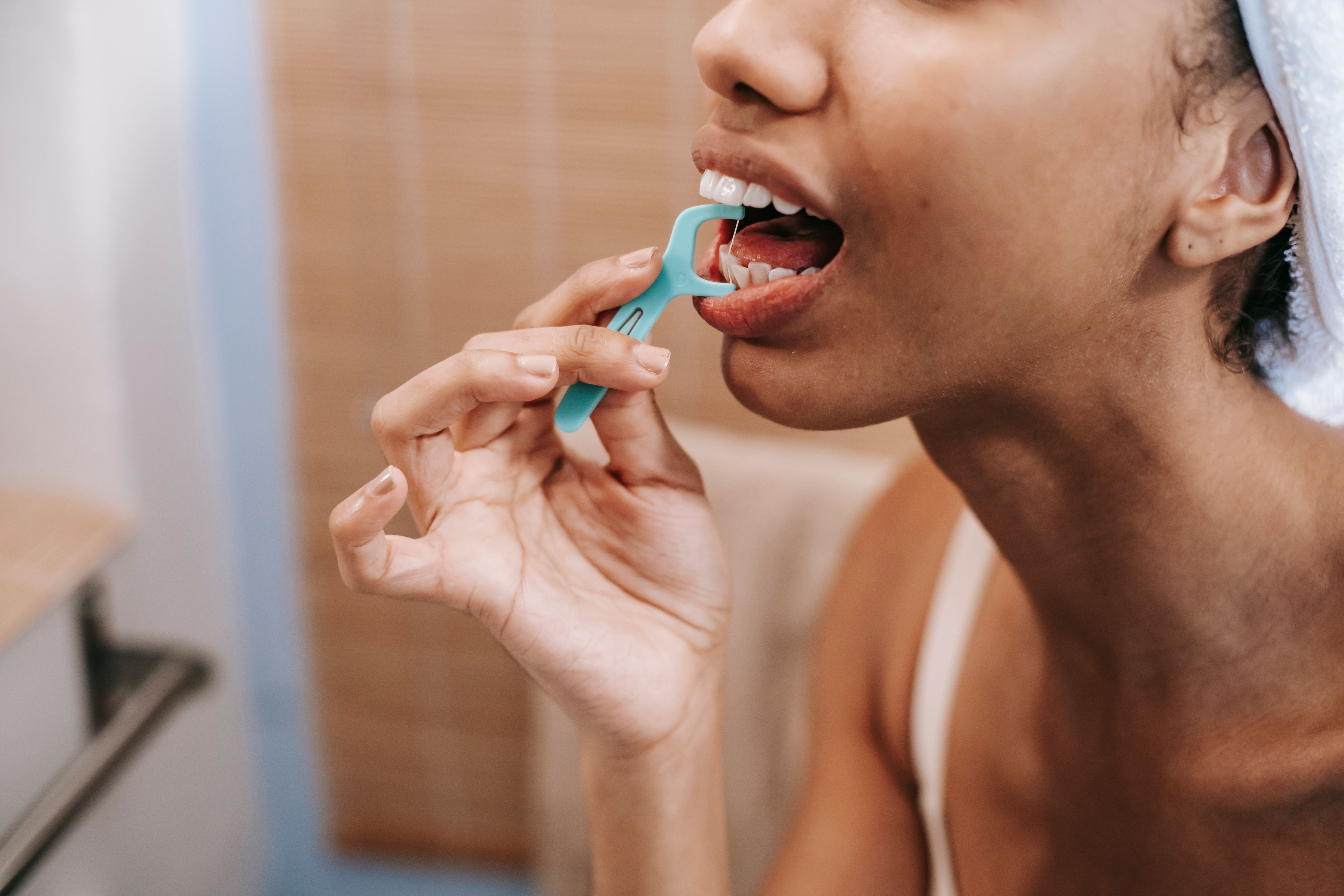 A woman flossing her teeth | Source: Pexels
