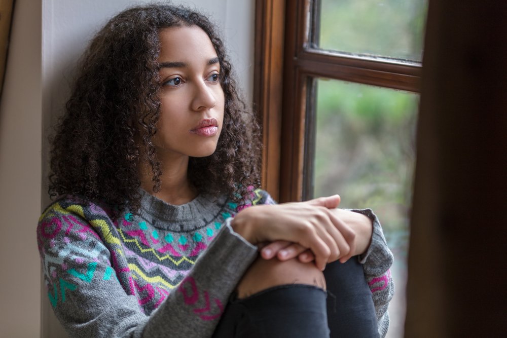 A photo of a sad woman looking out of a window. | Photo: Shutterstock