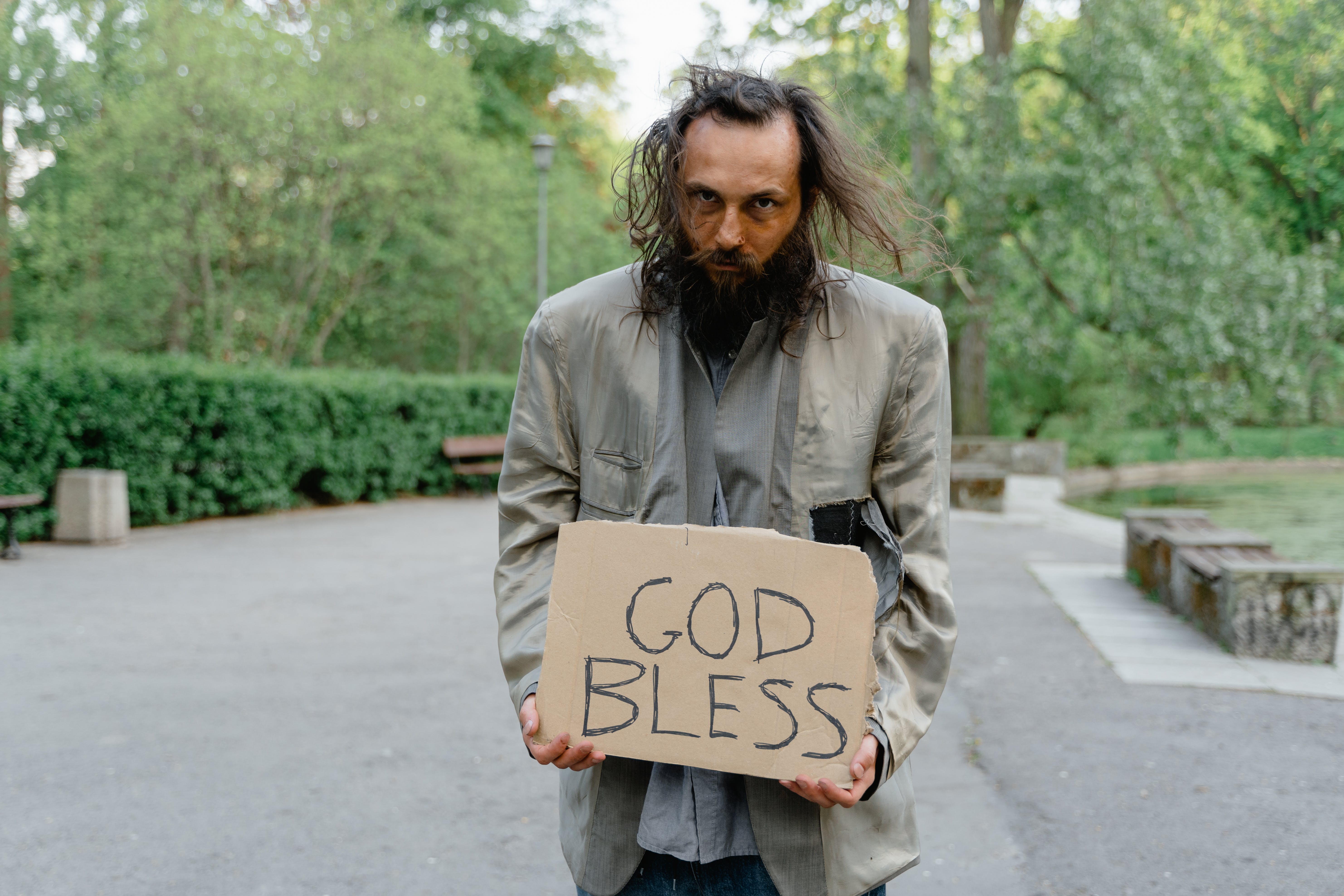 A homeless man standing with a sign on the road | Source: Pexels