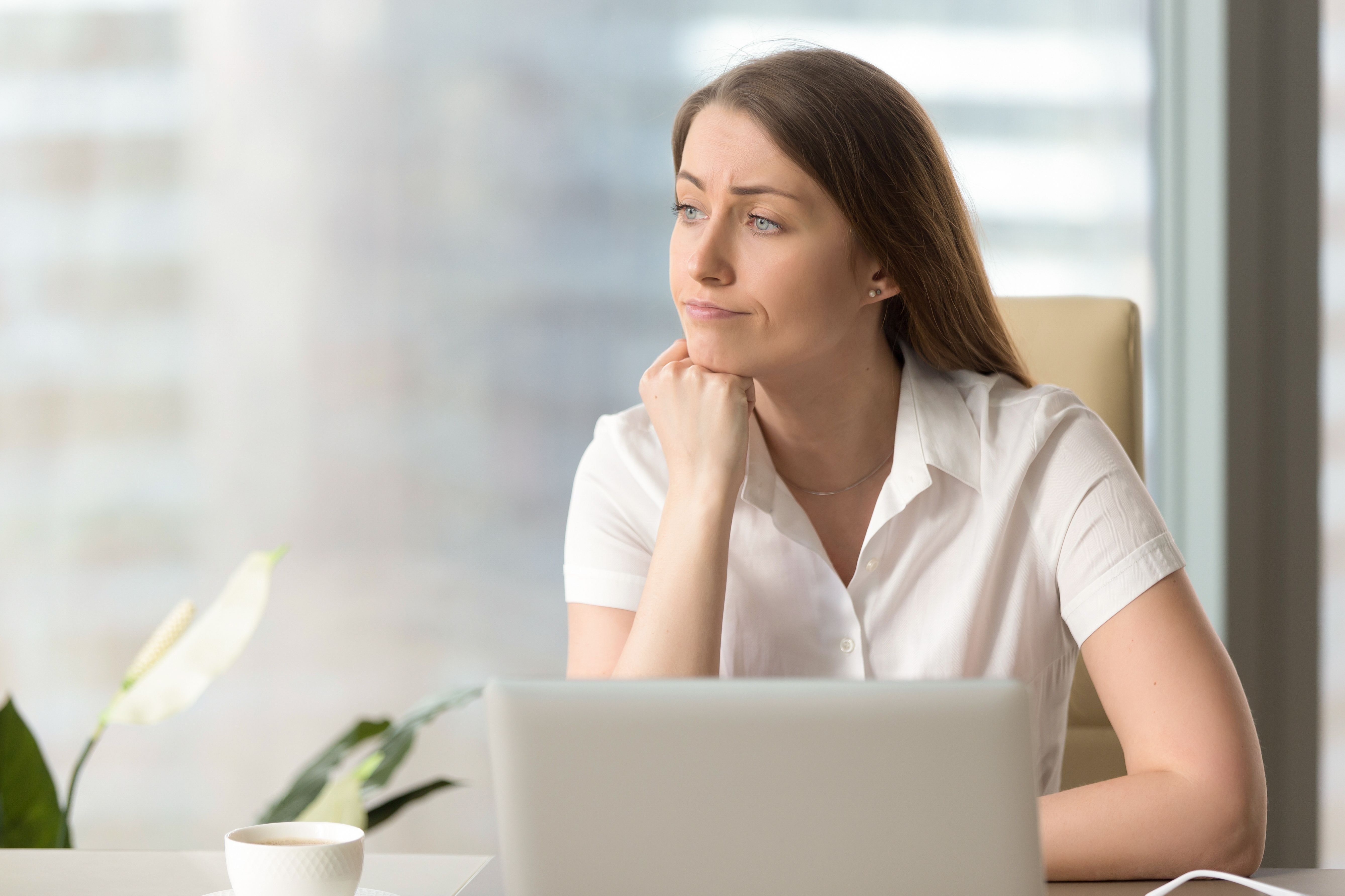 A woman using her laptop while looking out the window. | Source: Shutterstock