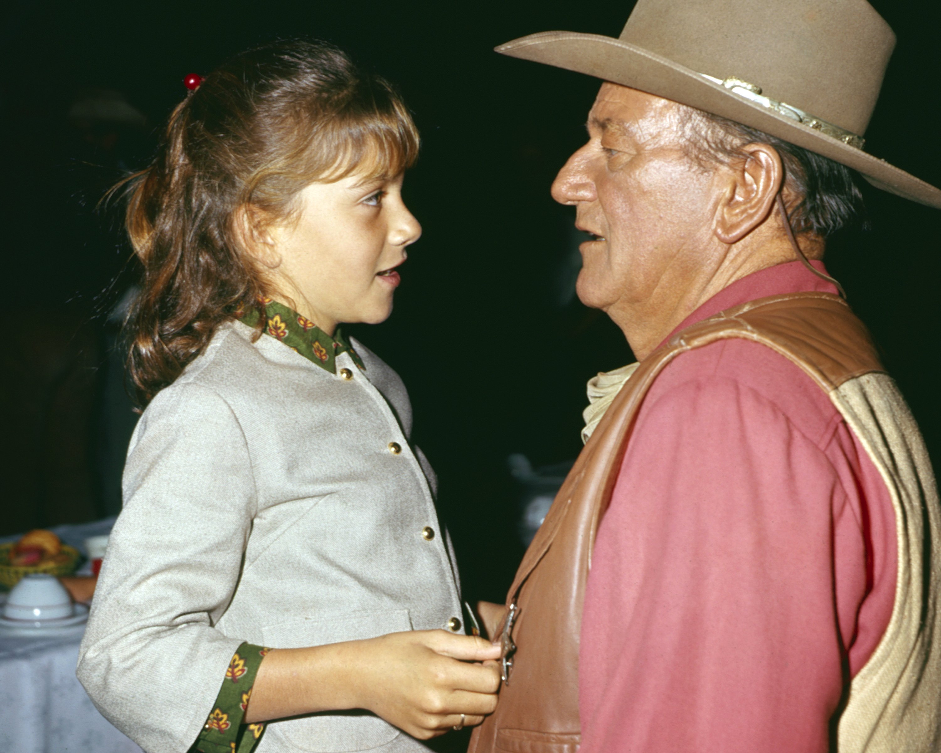 American actor John Wayne (1907 - 1979) talks with his daughter Aissa in an unspecified restaurant, 1967 | Source: Getty Images