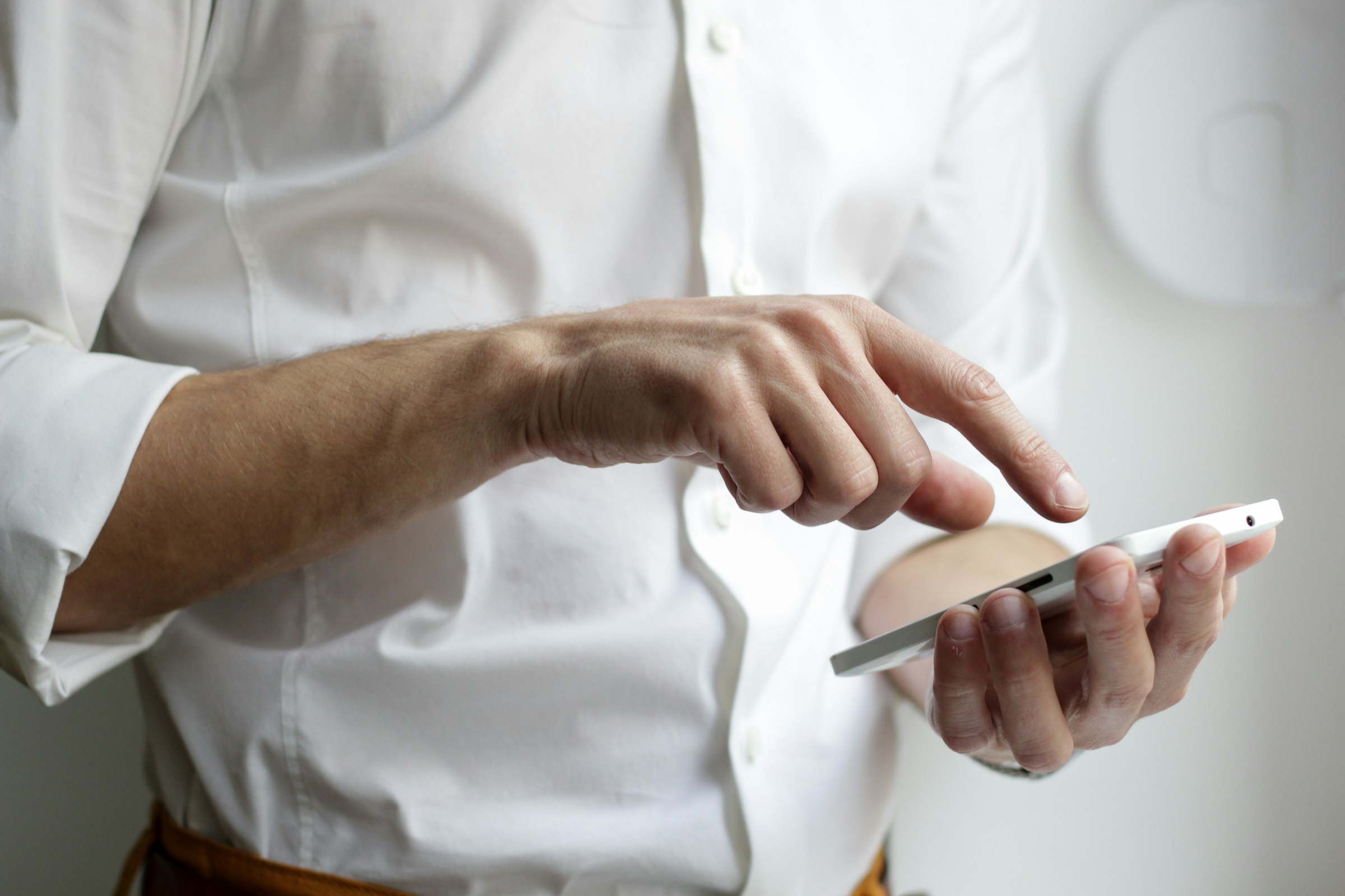 A closeup of a man in a white shirt using a smartphone | Source: Midjourney