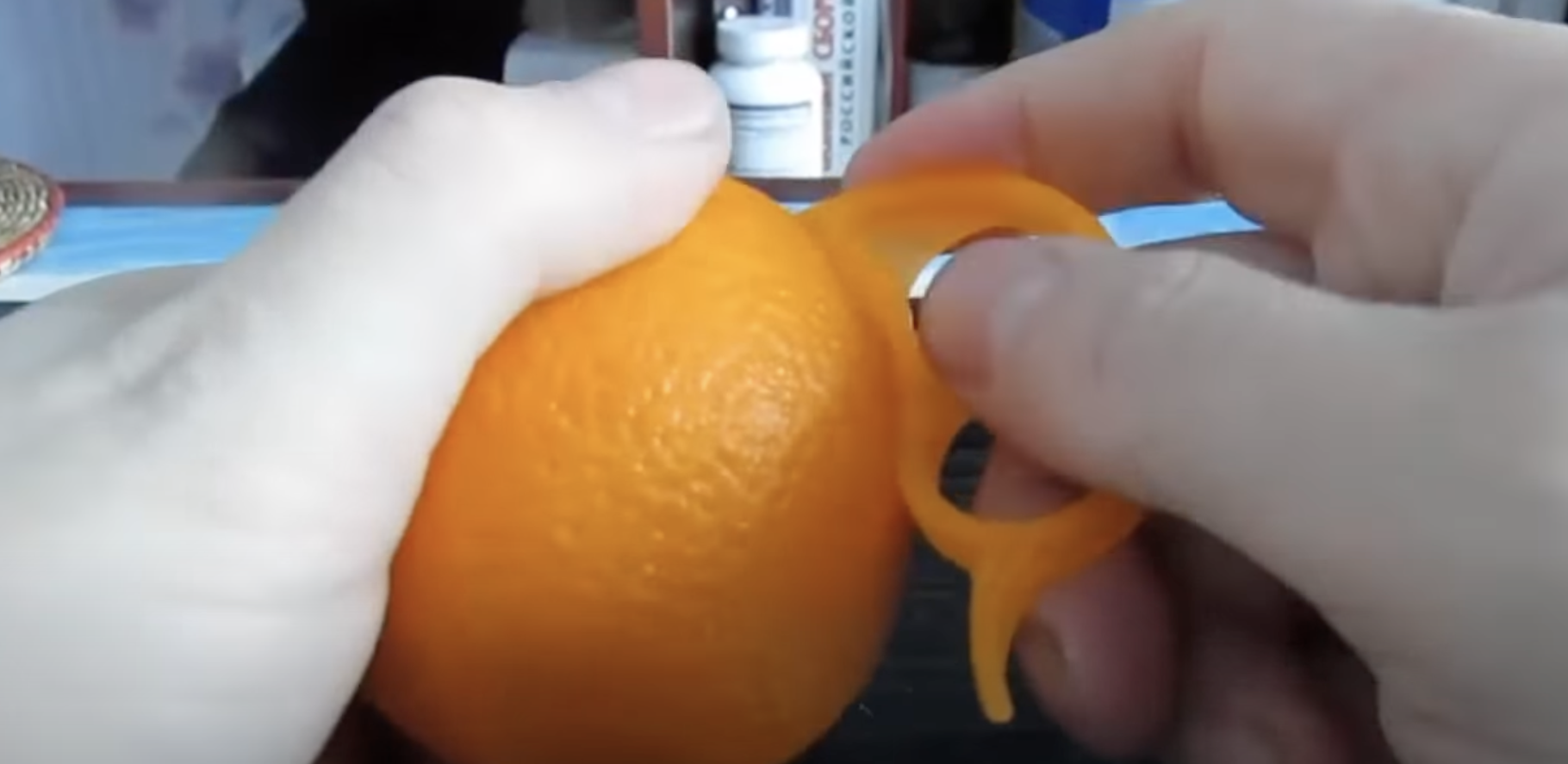 A person using an orange peeler | Source: youtube.com/@zetira4582