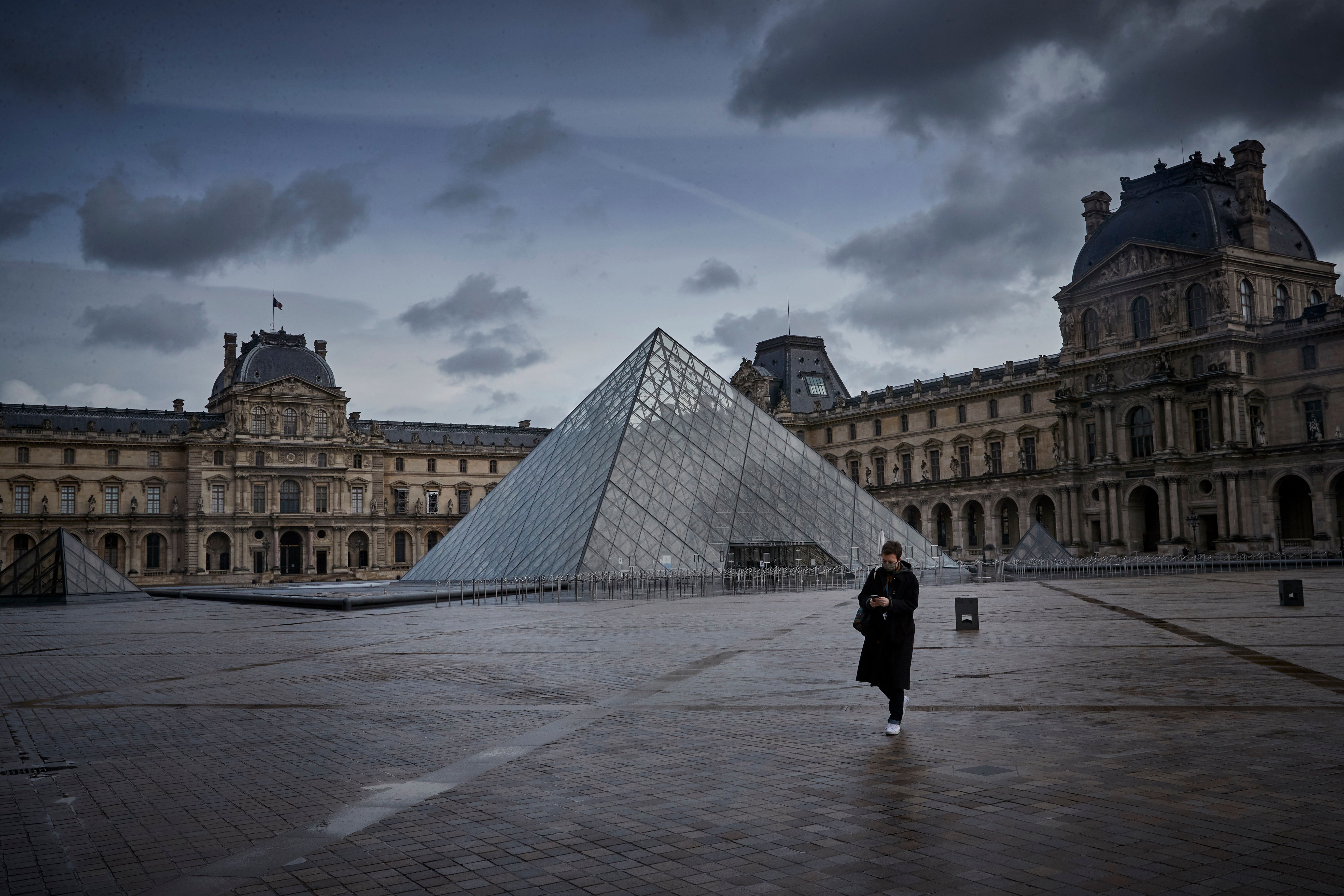 Un parisien se promène devant le musée du Louvre fermé le 18 mars 2021 à Paris. | Photo : Getty Images