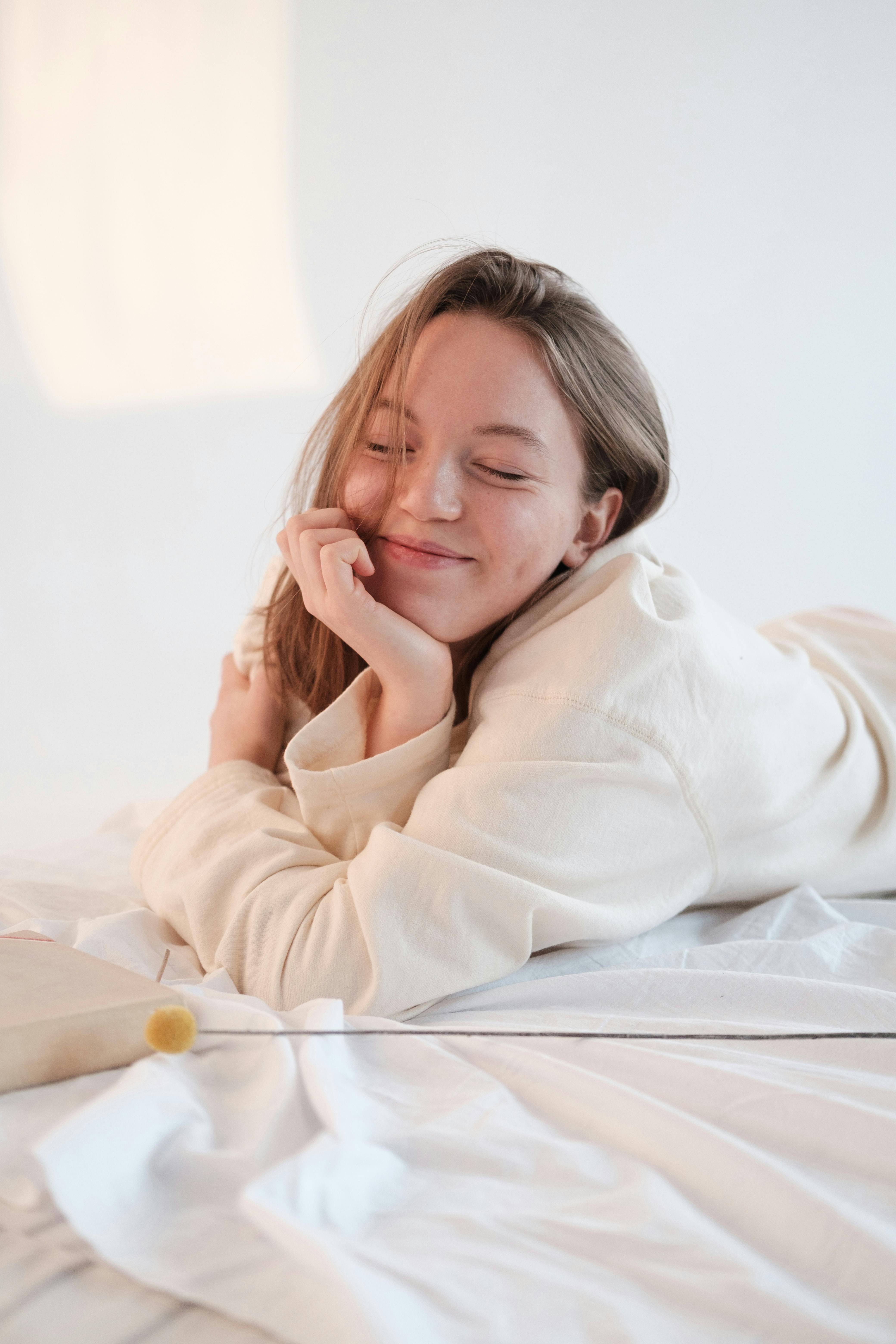 A happy woman lying on a bed | Source: Pexels