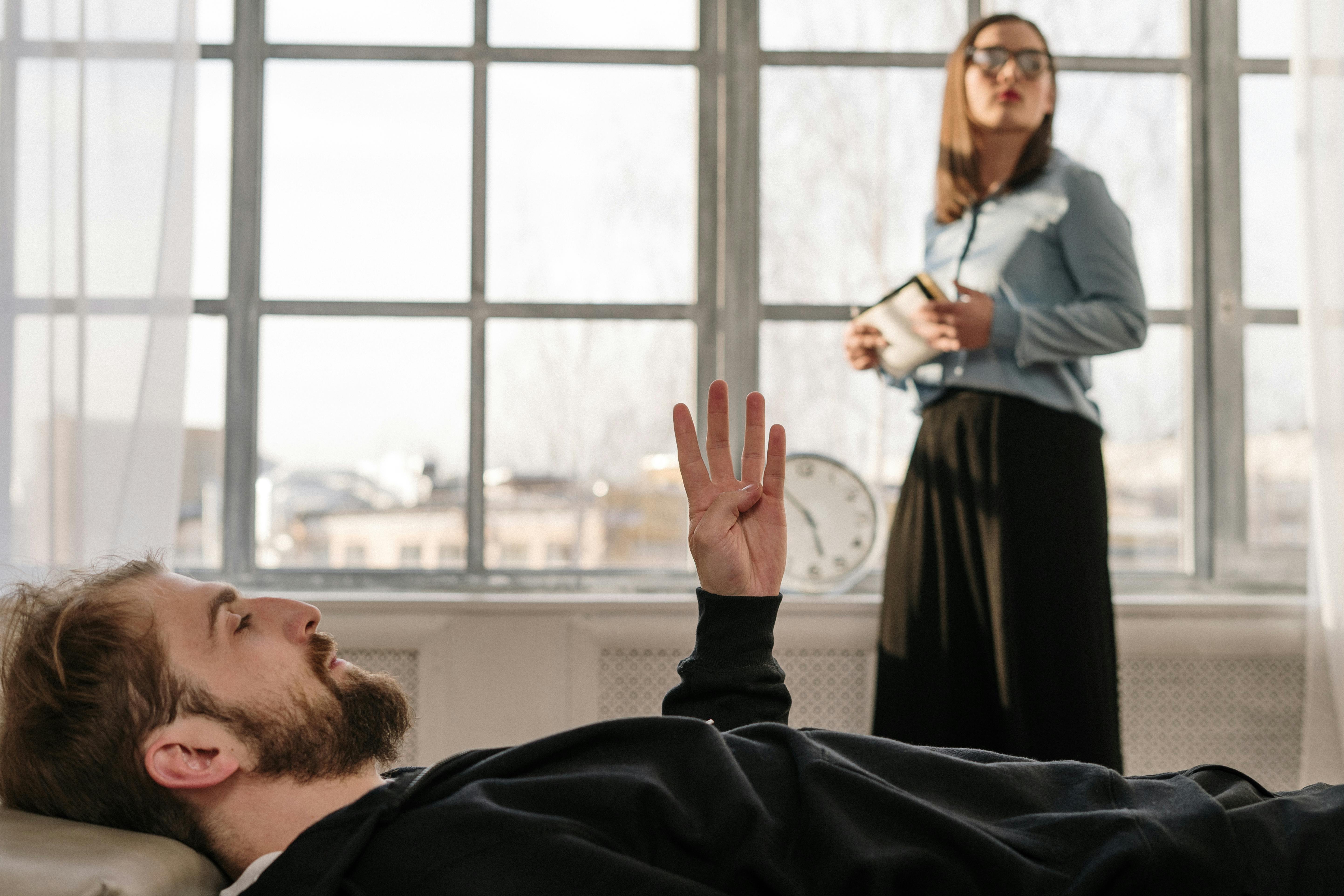 A man lying on a couch talking to a standing woman | Source: Pexels