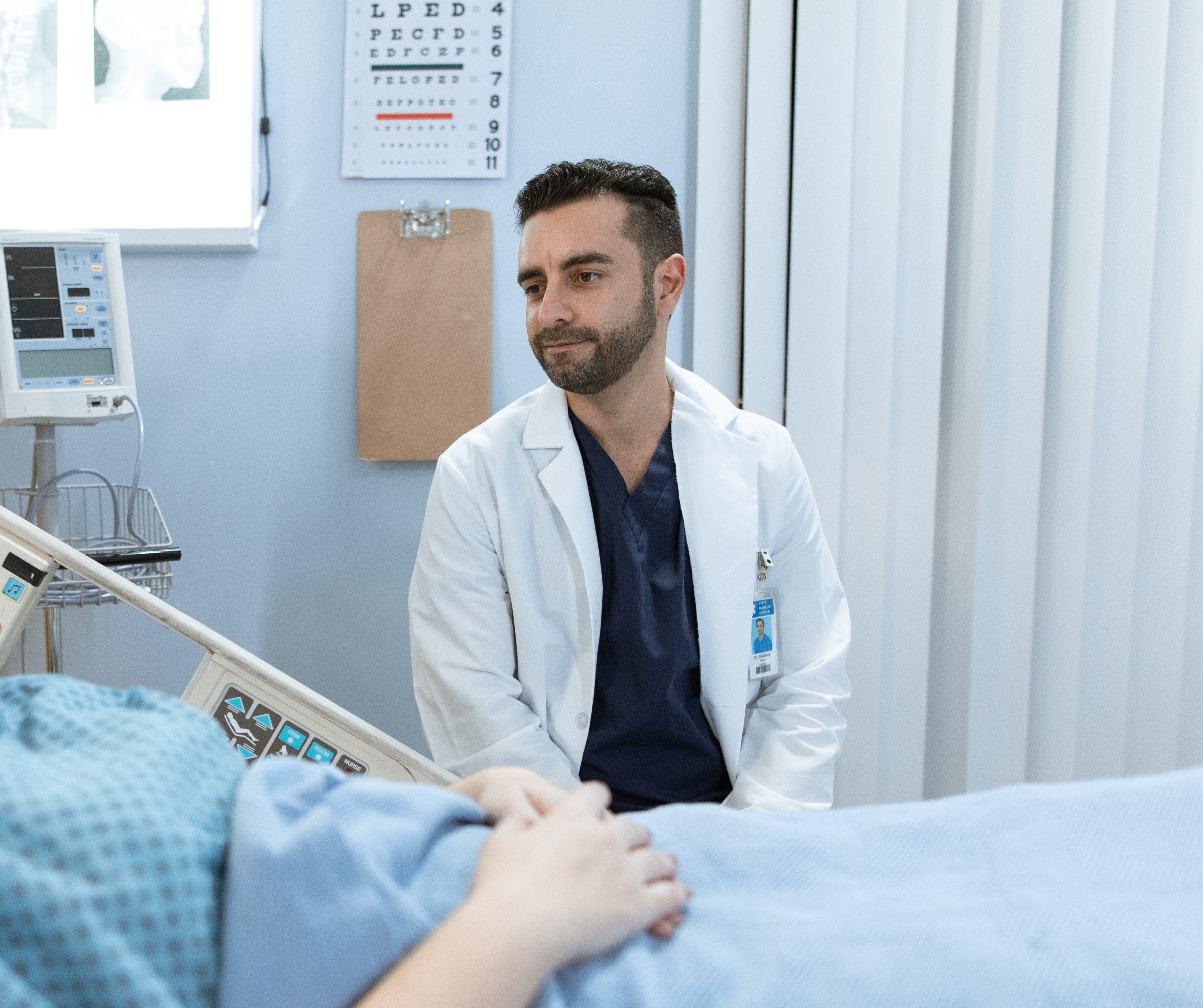 Un doctor joven habla con un paciente en camilla. | Foto: Pexels