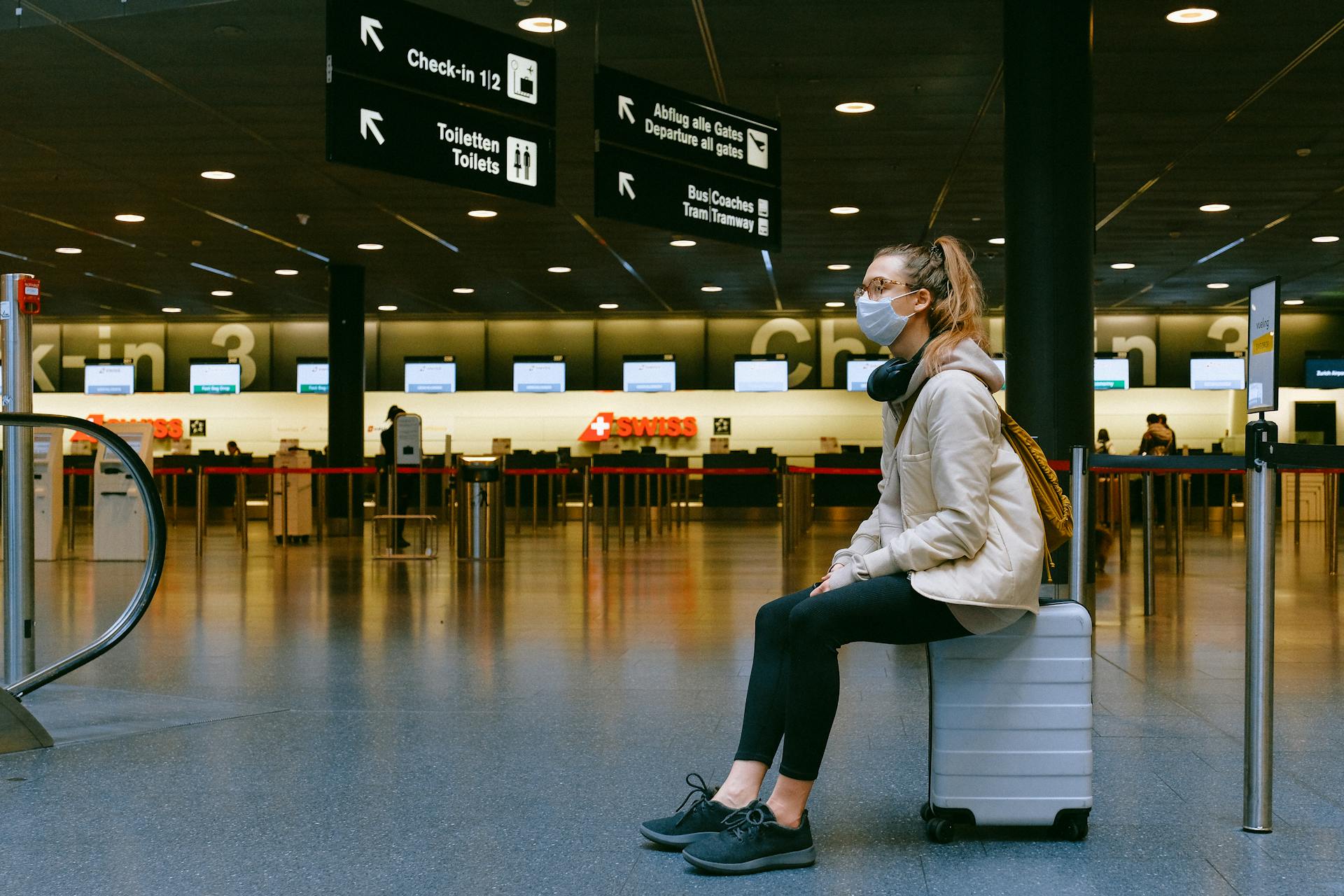 Woman sitting on a suitcase at an airport | Source: Pexels