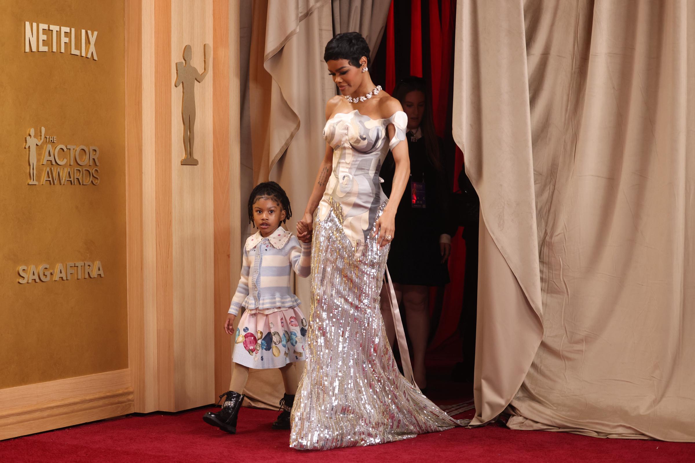 Teyana Taylor walks the red carpet at the 32nd Annual Screen Actors Guild Awards with Rue Rose Shumpert in Los Angeles. Teyana shines in a sculptural gown as Rue holds her hand in a cute top and skirt.