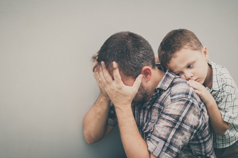Trauriger Sohn, der tagsüber seinen Vater an der Wand umarmt. I Quelle: Shutterstock
