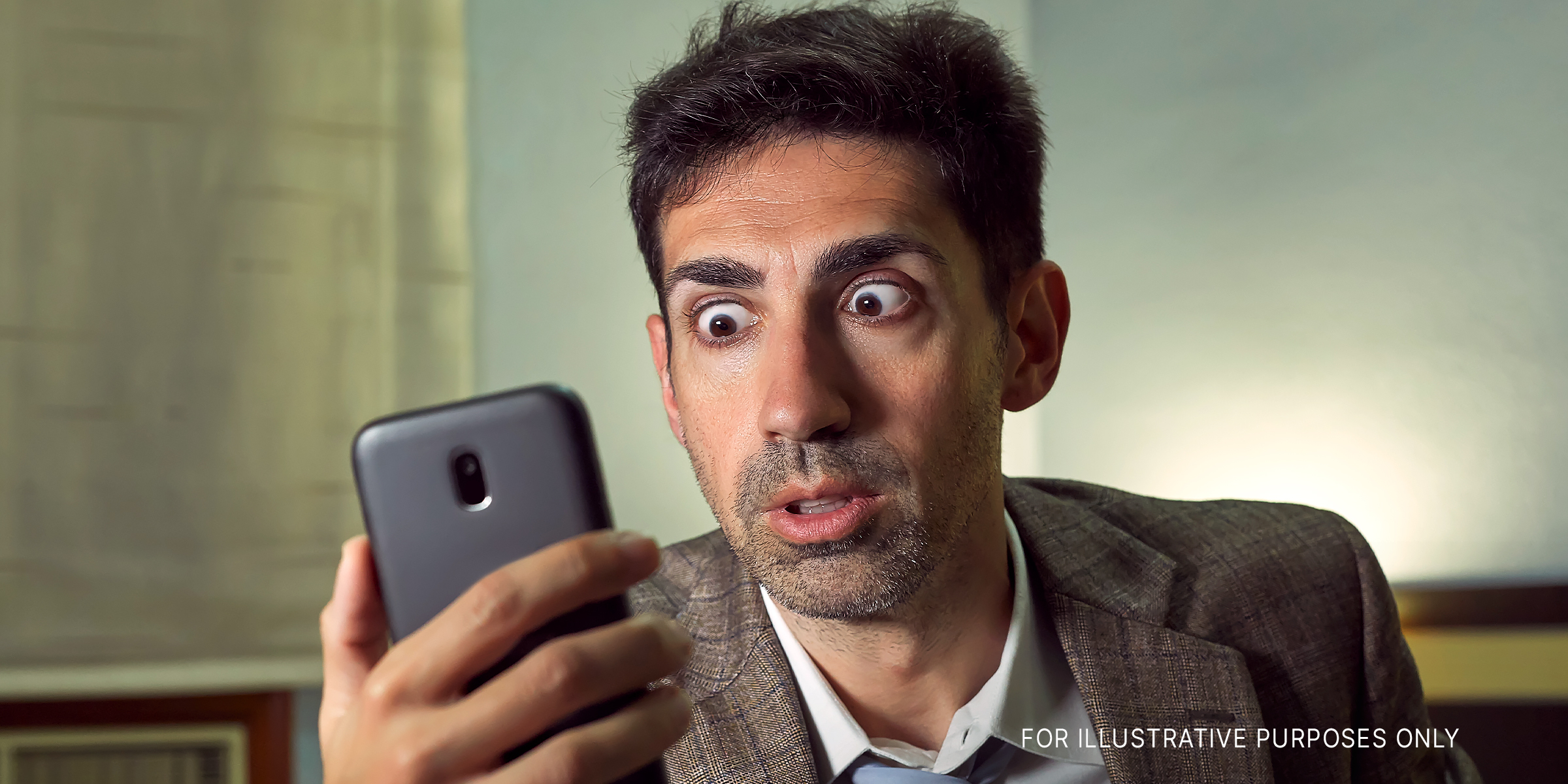 A man looking at his phone with wide eyes | Source: Shutterstock