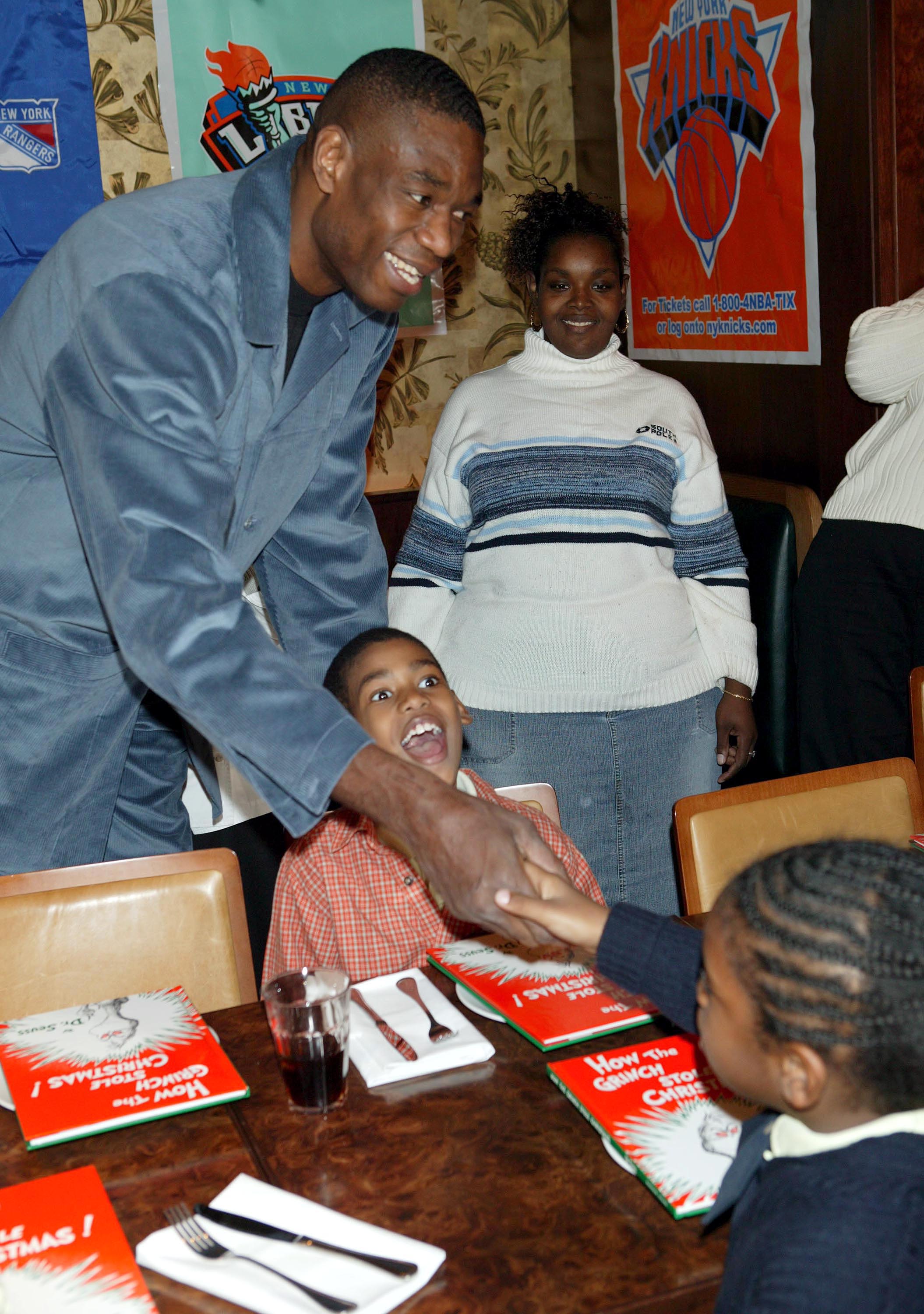 Dikembe Mutombo greets children at the New York Knicks' "Read-To-Achieve" program at Rocco's Restaurant in New York City on December 15, 2003 | Source: Getty Images