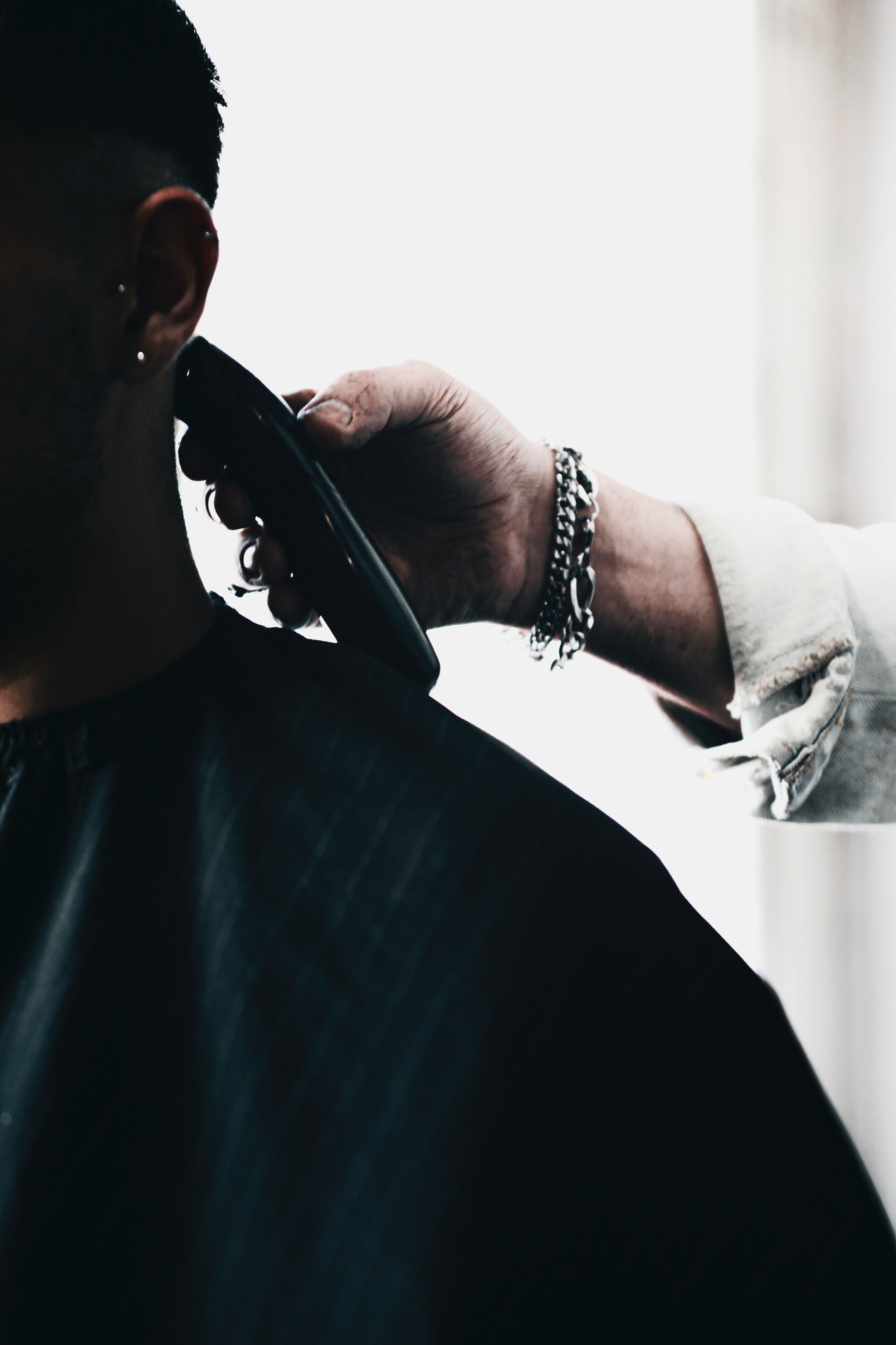 Barber holding a trimmer near a person's head. | Source: Unsplash
