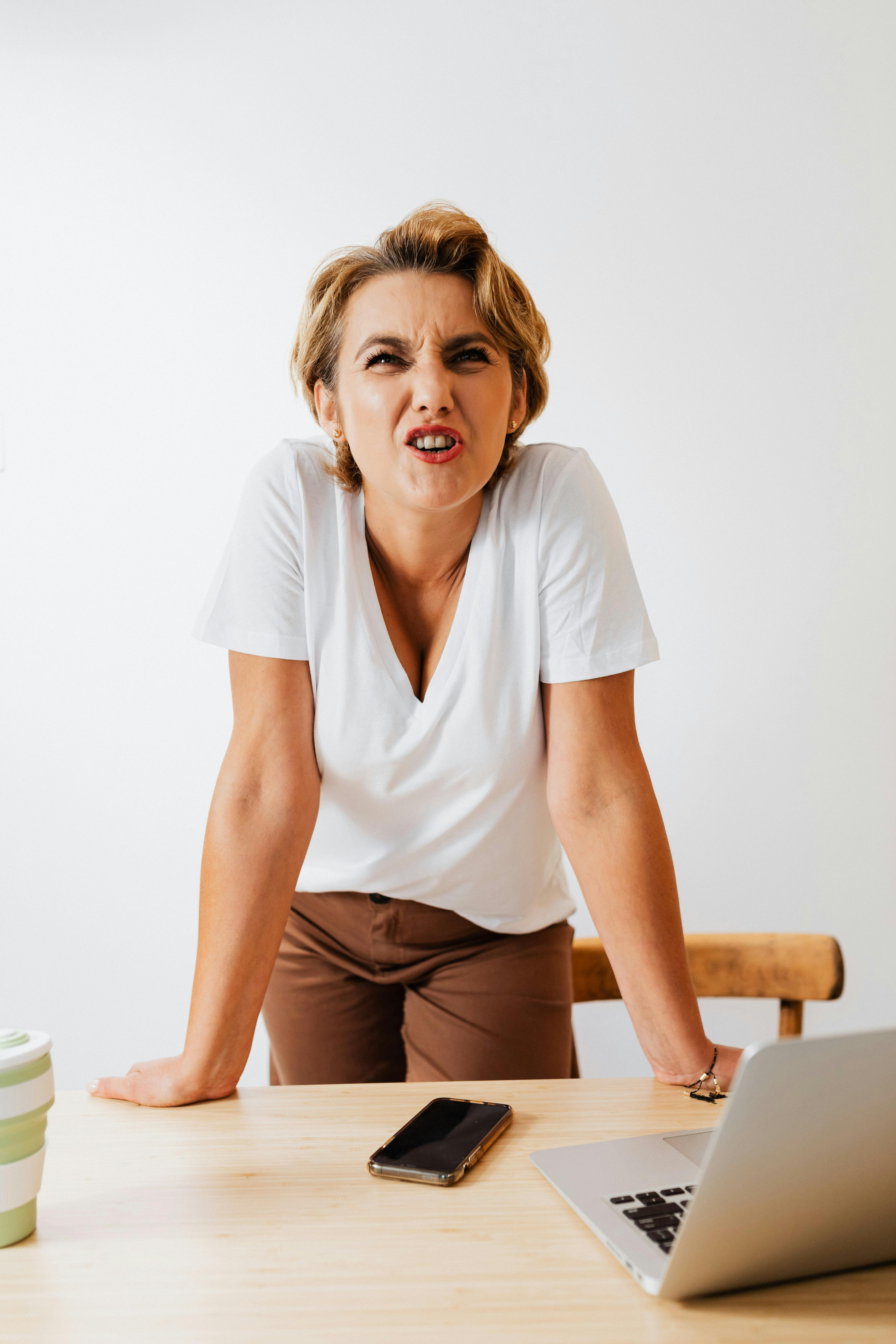 A woman reacting angrily while balancing her hands on a table | Source: Pexels