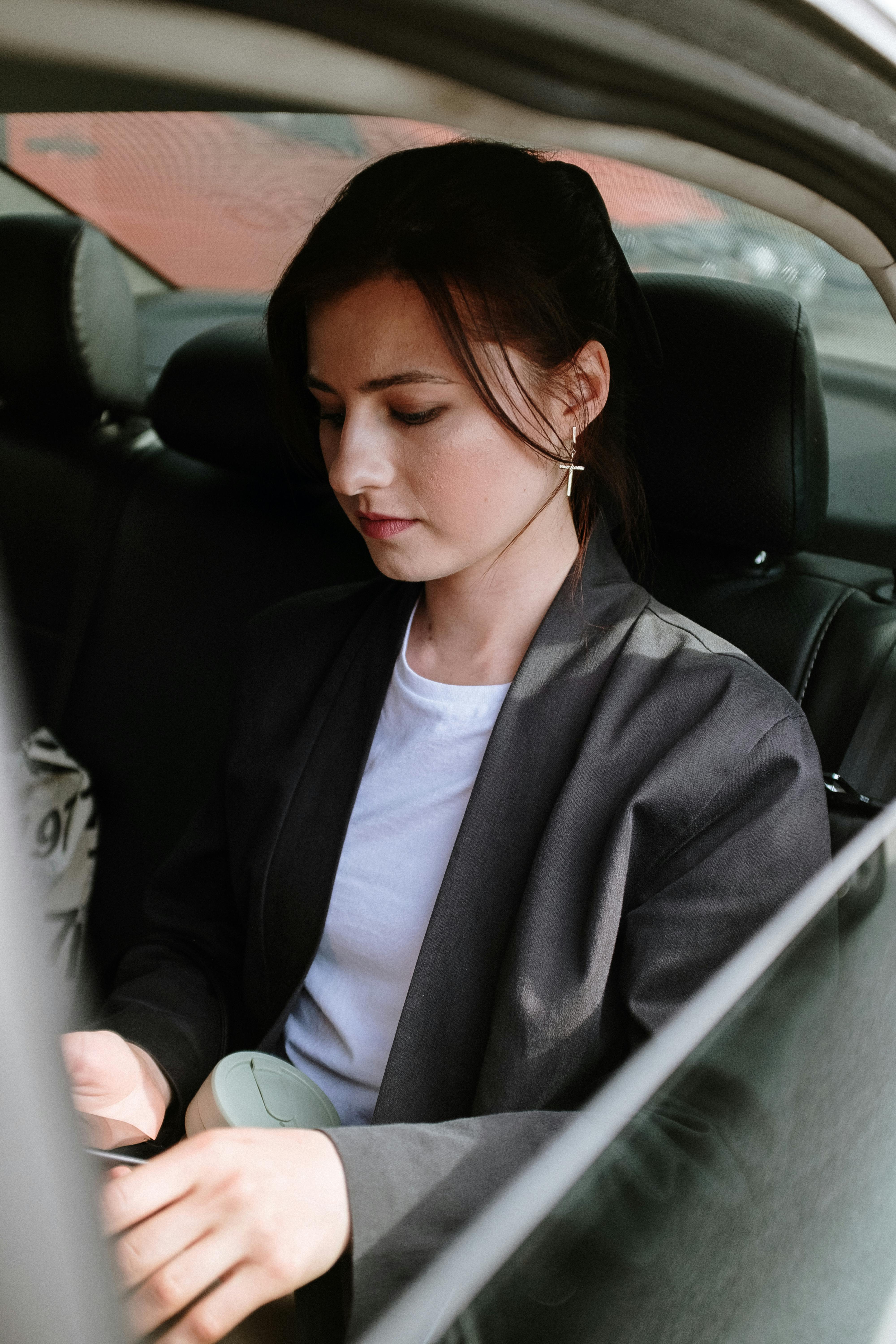 An unhappy looking woman looking at something while in a car | Source: Pexels