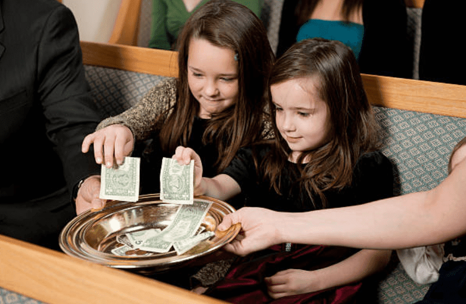 Two young girls give money offerings in church | Source: Getty Images