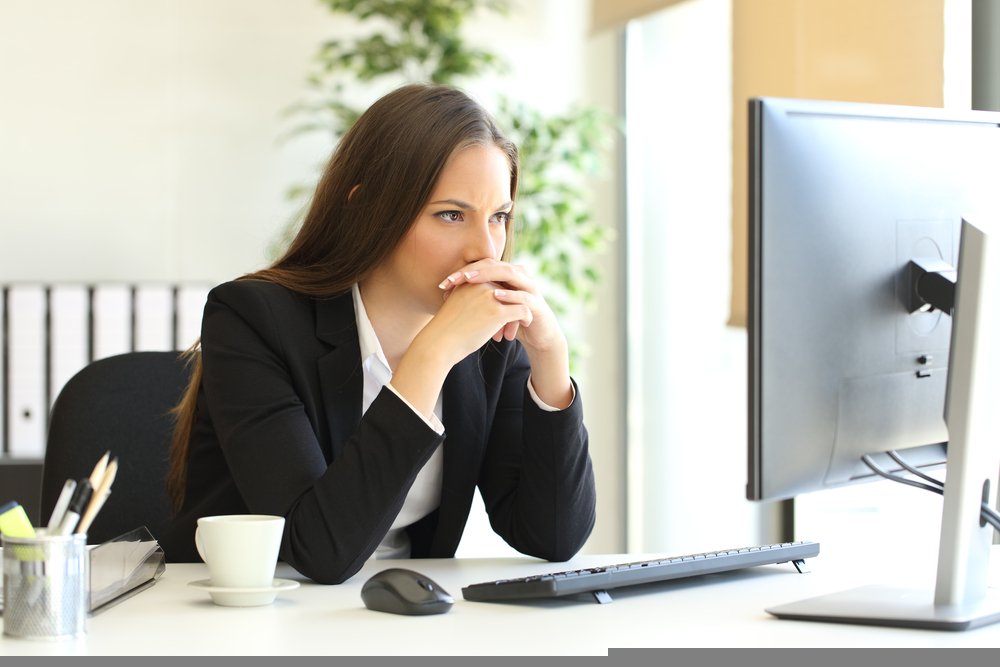 A working woman deeply thinking about something while looking at her desktop. | Source: Shutterstock