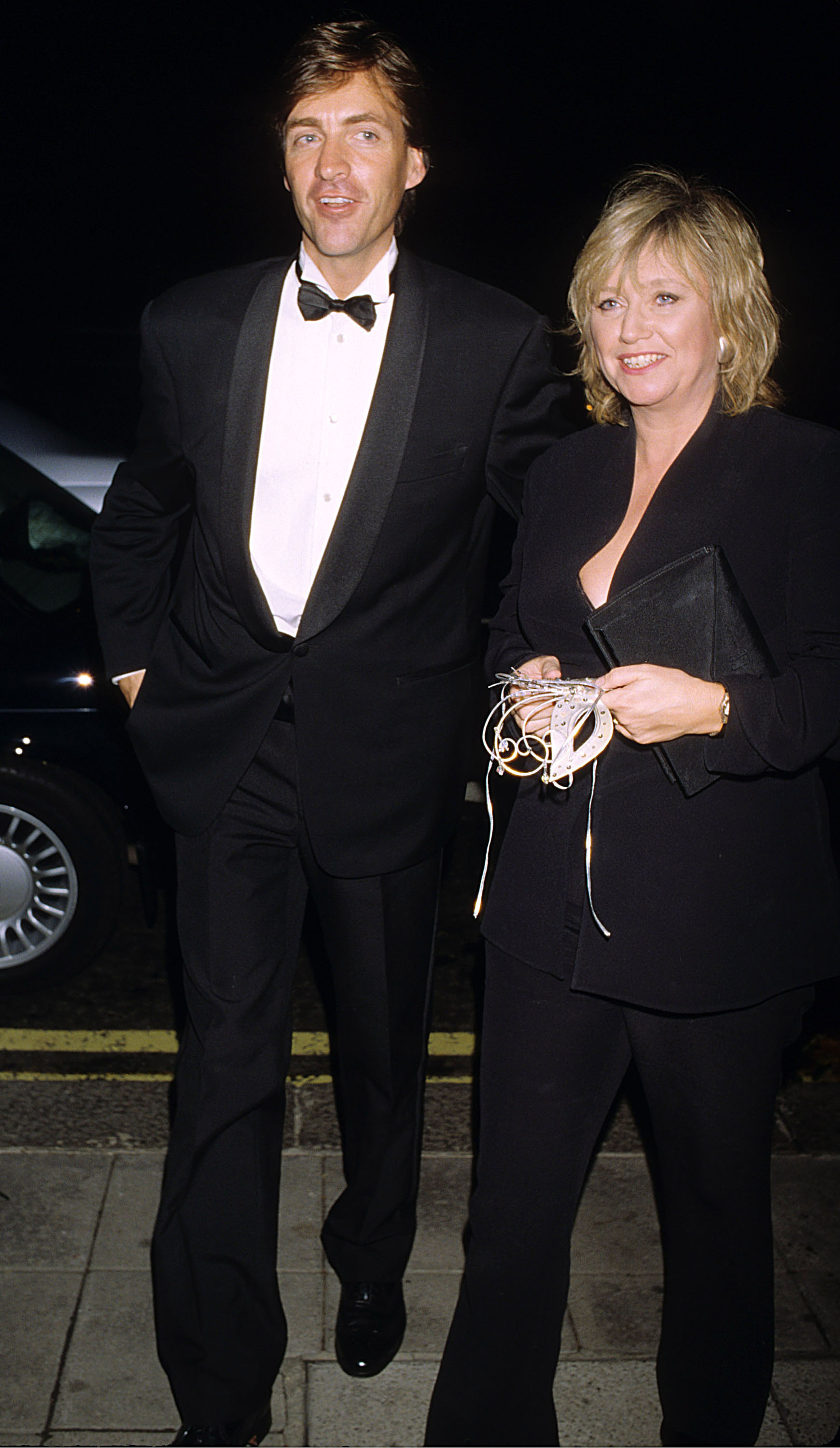 Richard Madeley and Judy Finnigan are seen arriving in elegant eveningwear at a London event for "The Phantom of the Opera" on 9 October 1996, their polished appearance and relaxed smiles reflecting their status at the time as one of British television's most recognisable and admired couples, effortlessly transitioning from daytime screens to high-profile social occasions.