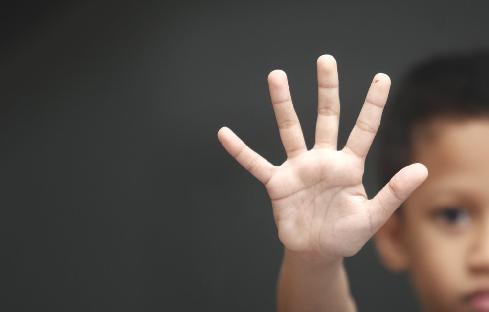 Un garçon lève une main pour dire "non". Photo : Shutterstock