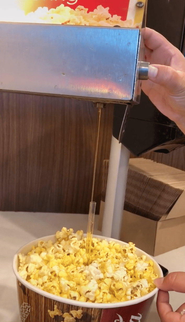 In a viral video, a woman demonstrates a hack on how to get butter to the bottom on the popcorn box | Photo: TikTok/colleenlepp